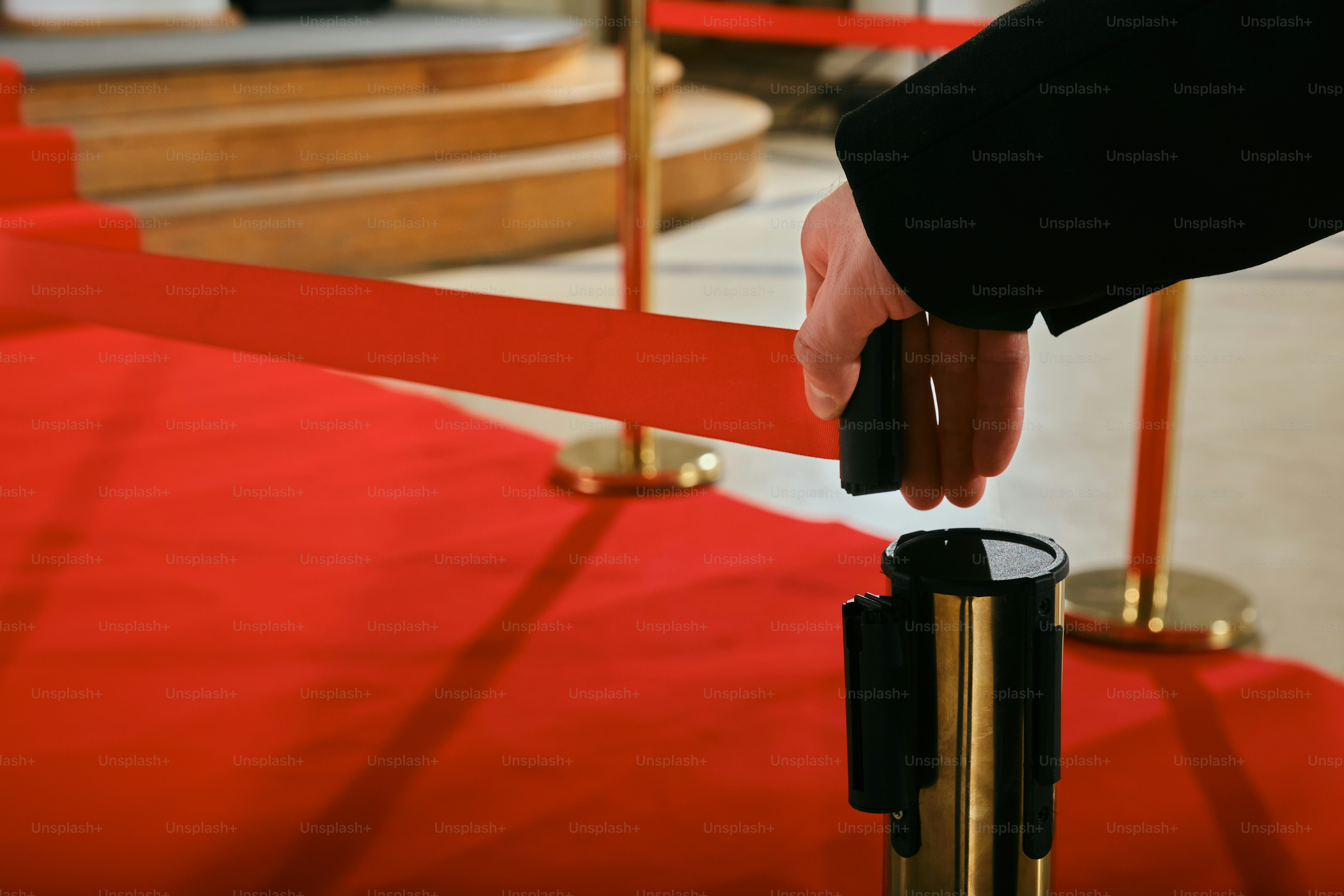 A hand reaching for a piece of metal on a red carpet