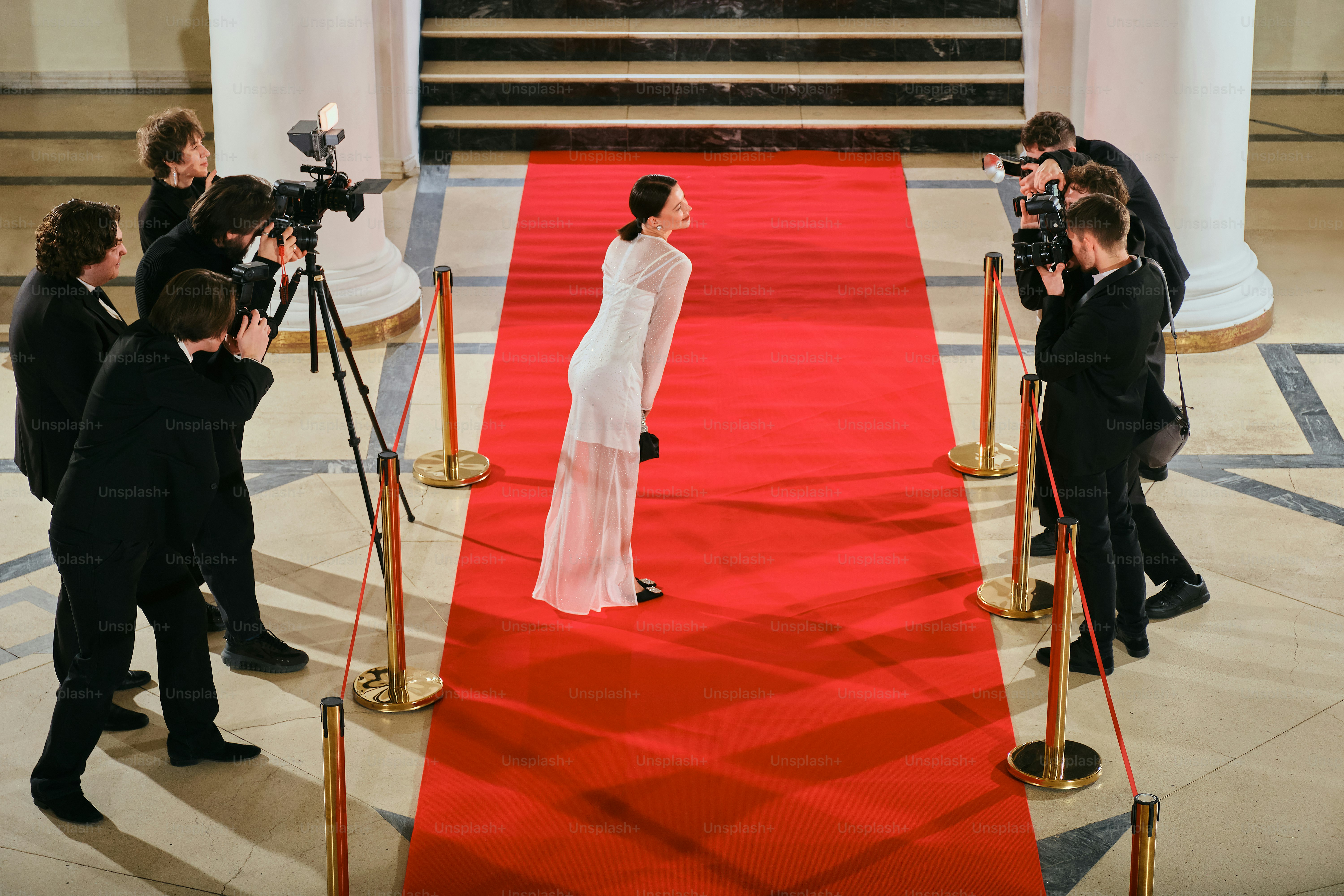 A woman in a white dress standing on a red carpet photo – Photographer ...
