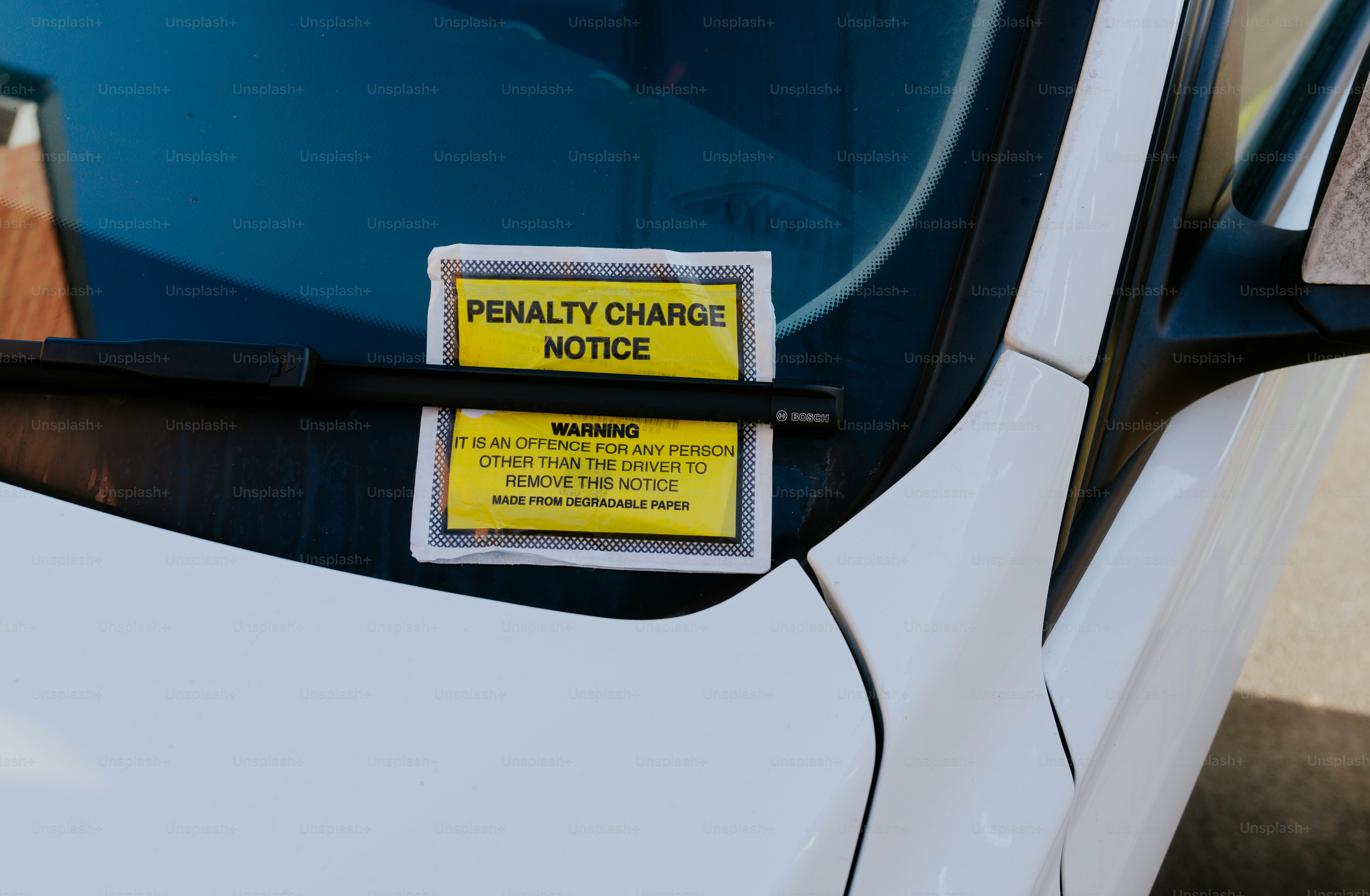 A white car with a yellow sticker on it