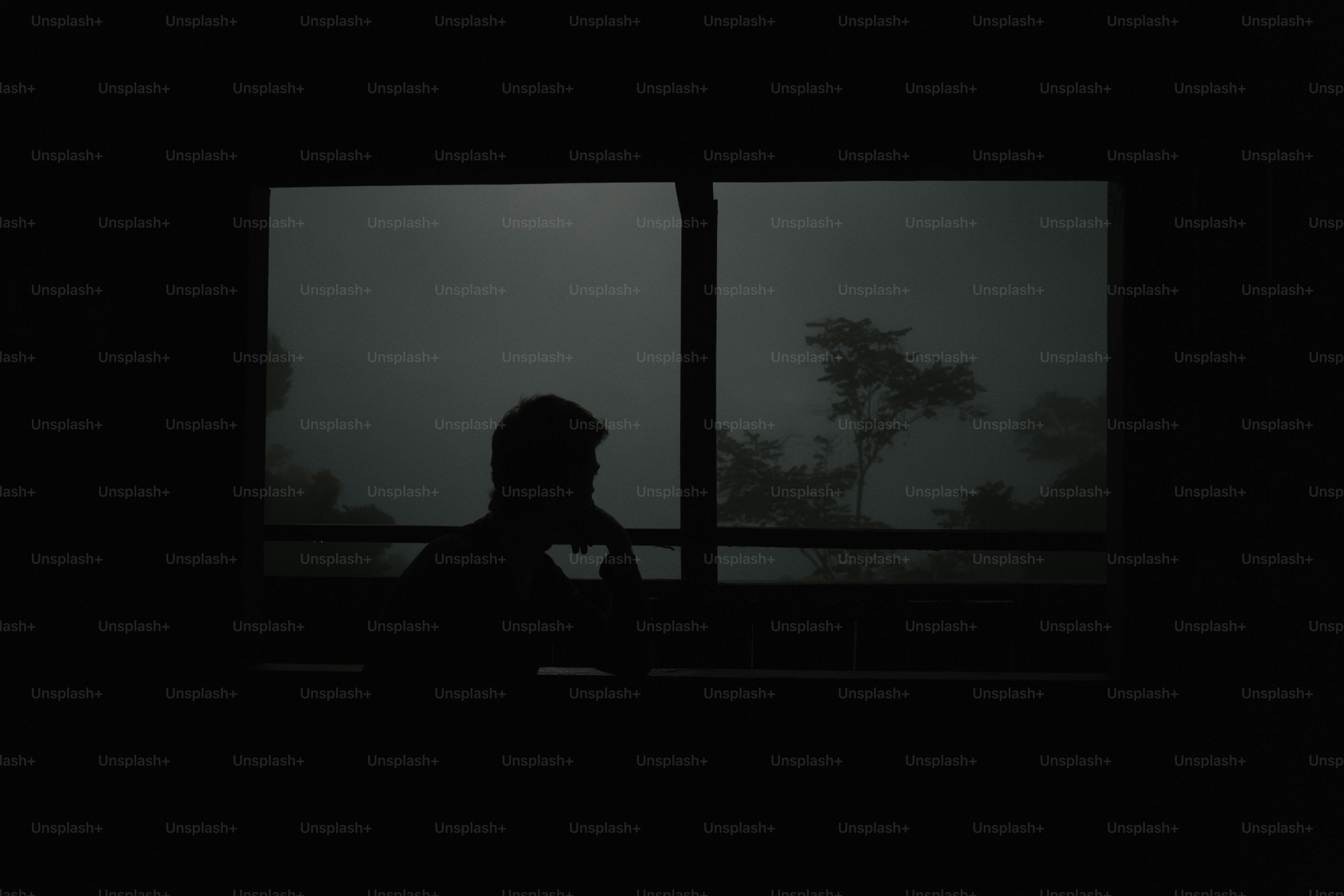 A person standing in front of a window in the dark