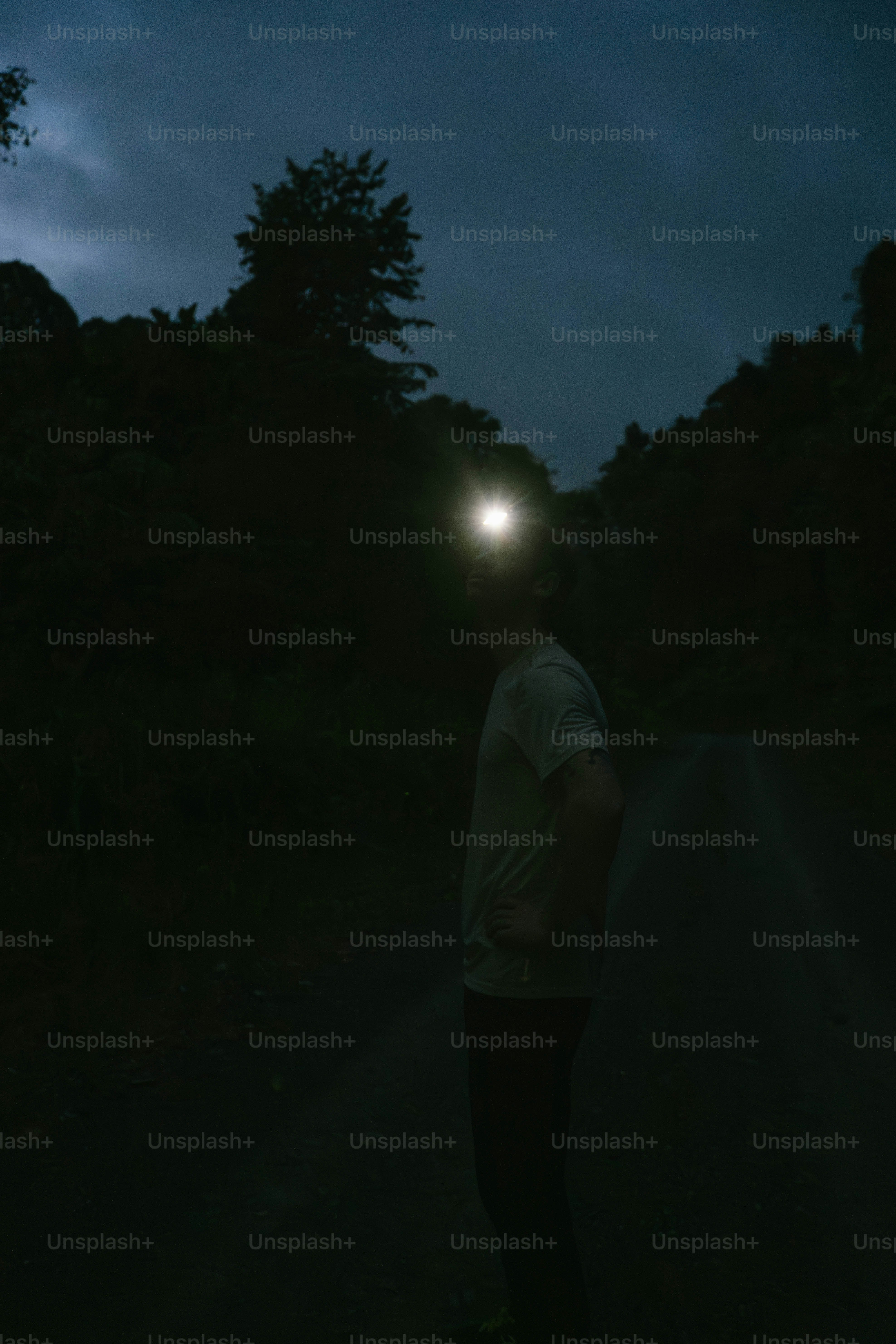 A man standing in the dark with a flashlight on his head