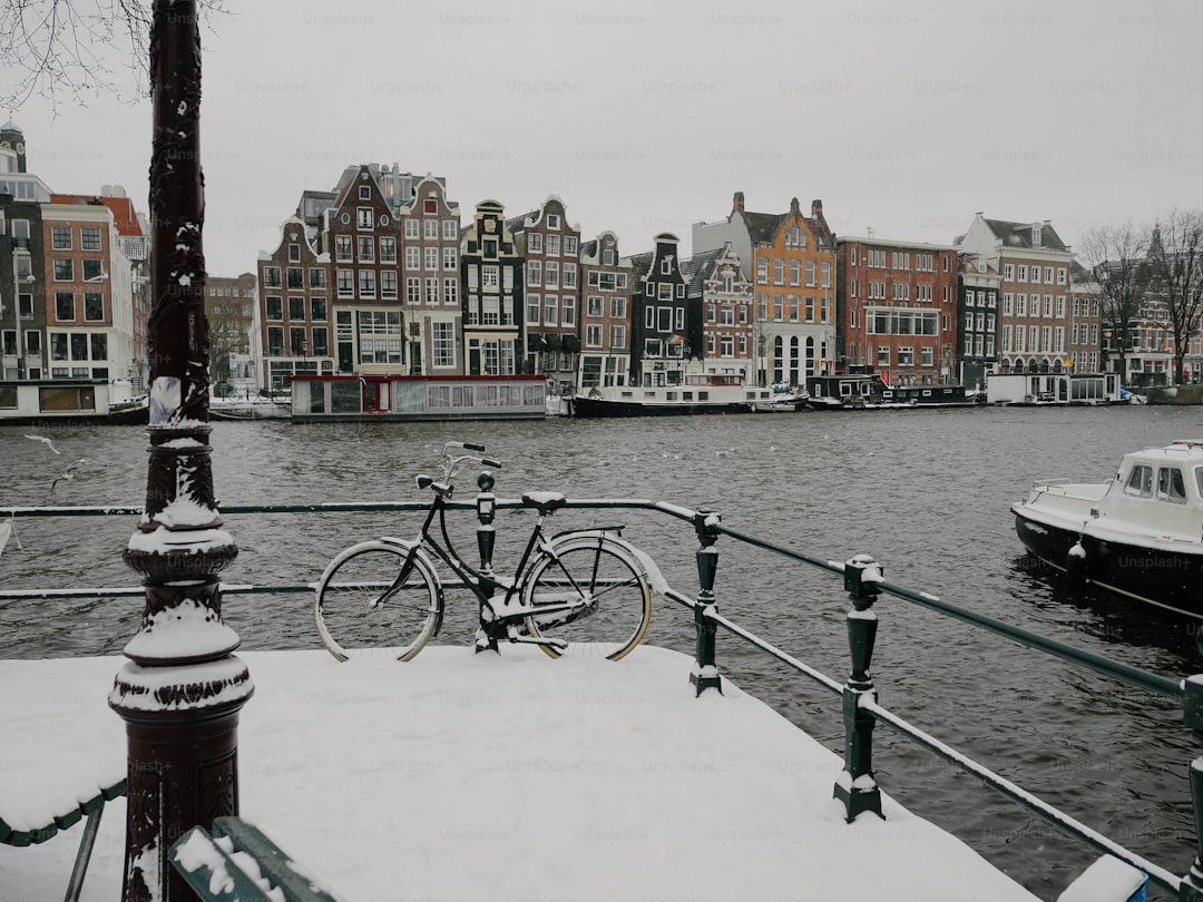 A bicycle is parked on a railing next to a body of water