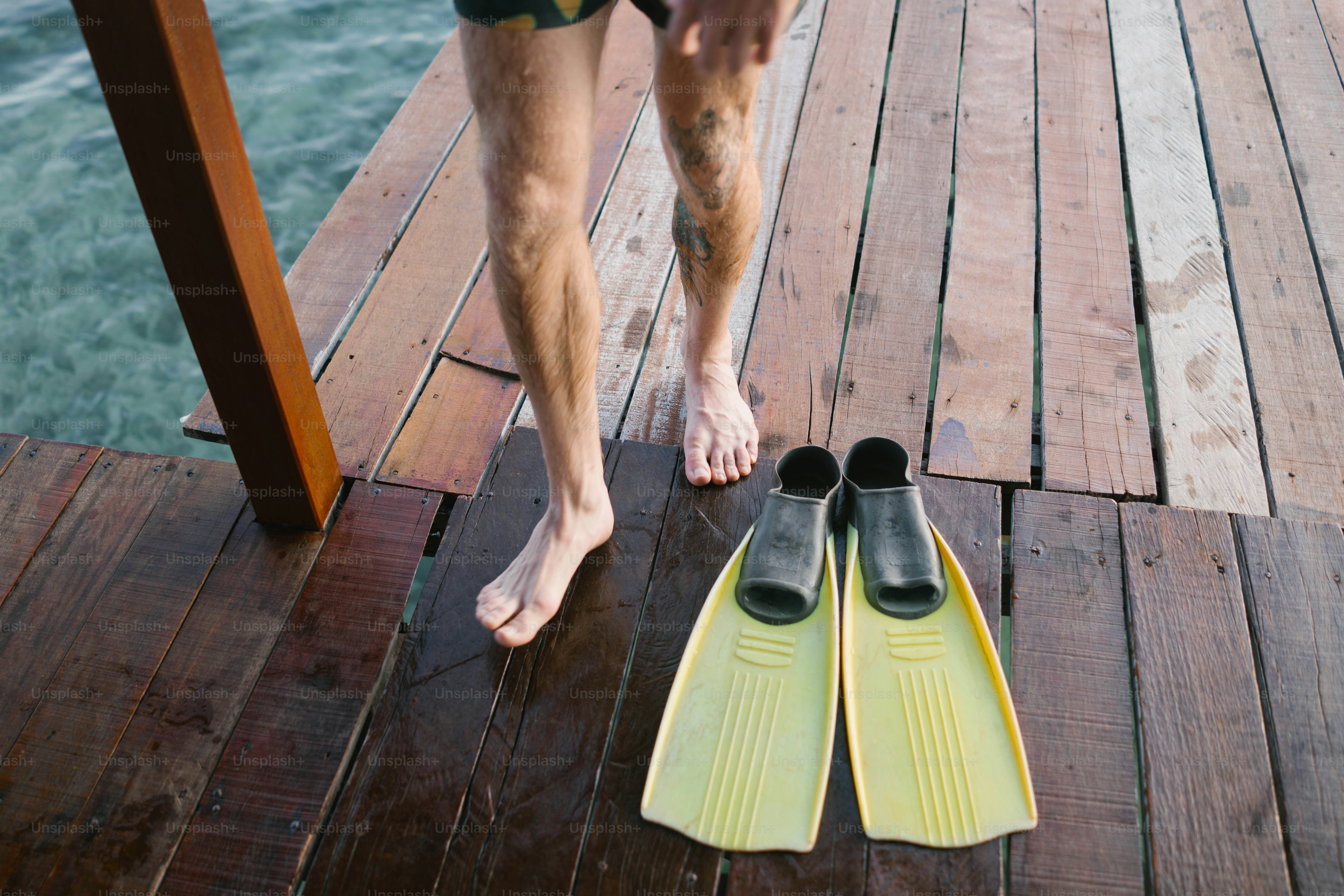 A man standing on a dock next to a pair of water skis