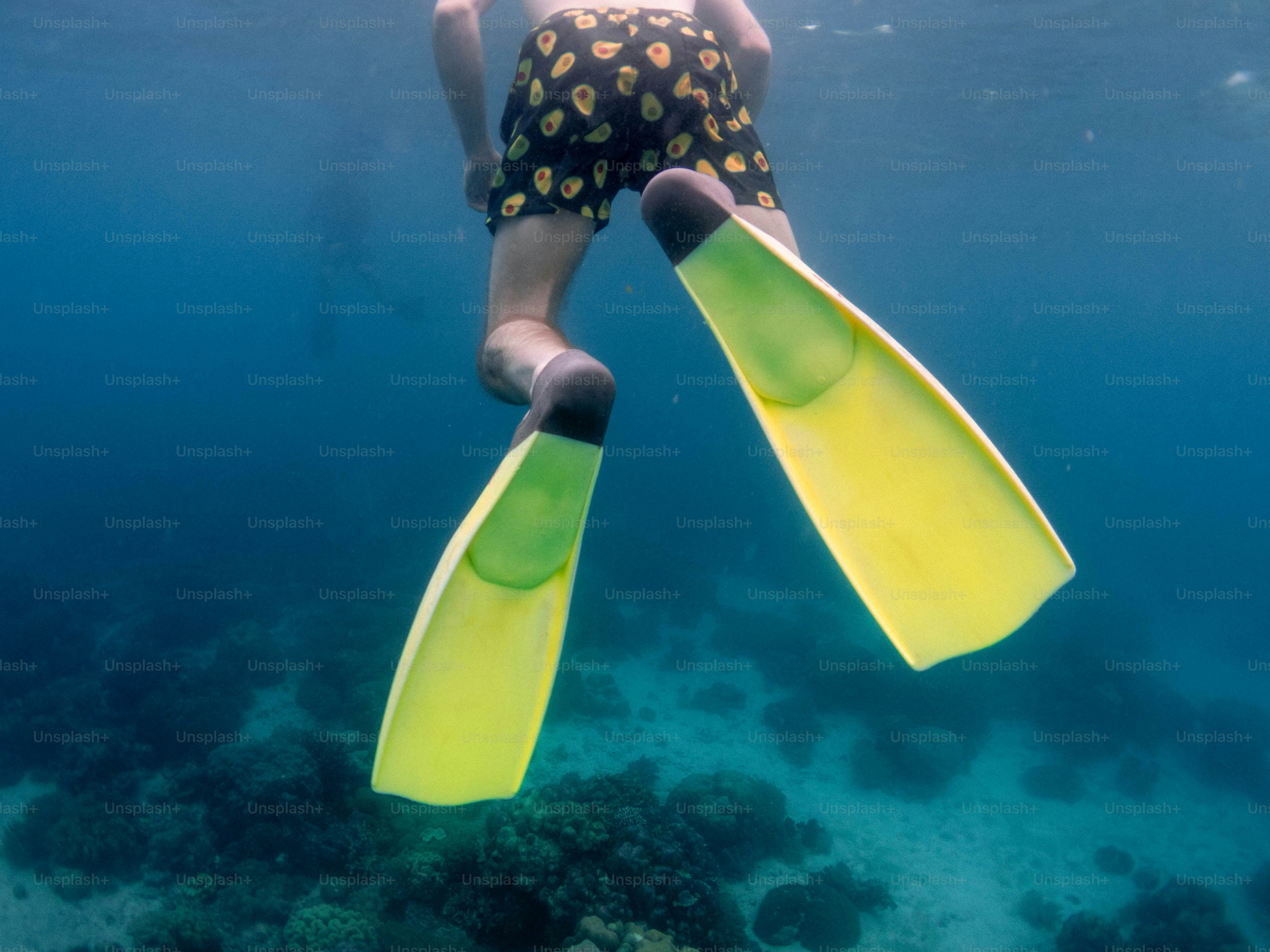 A young boy swimming in the ocean with a yellow board