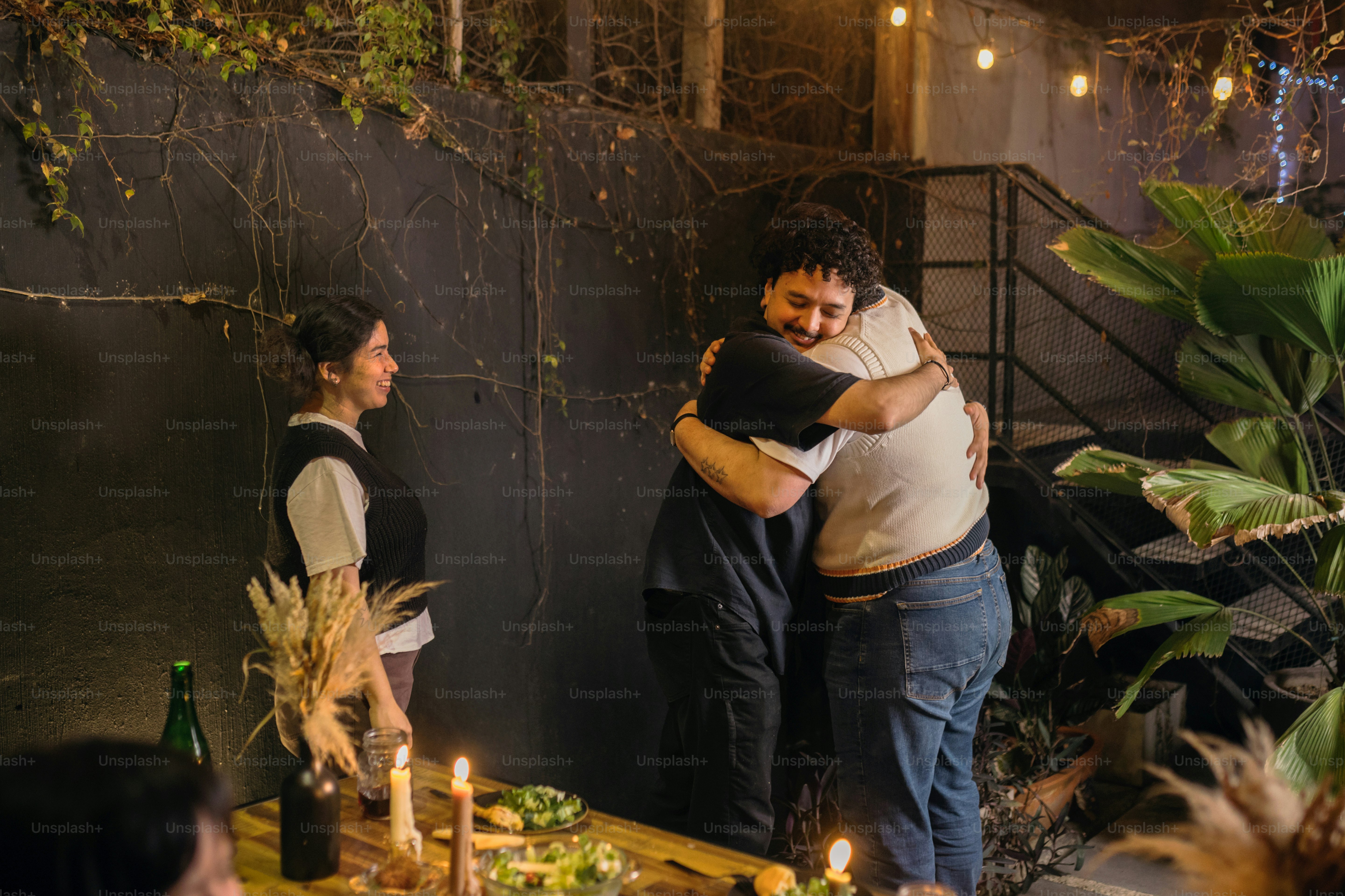 A couple of men hugging each other in front of a table