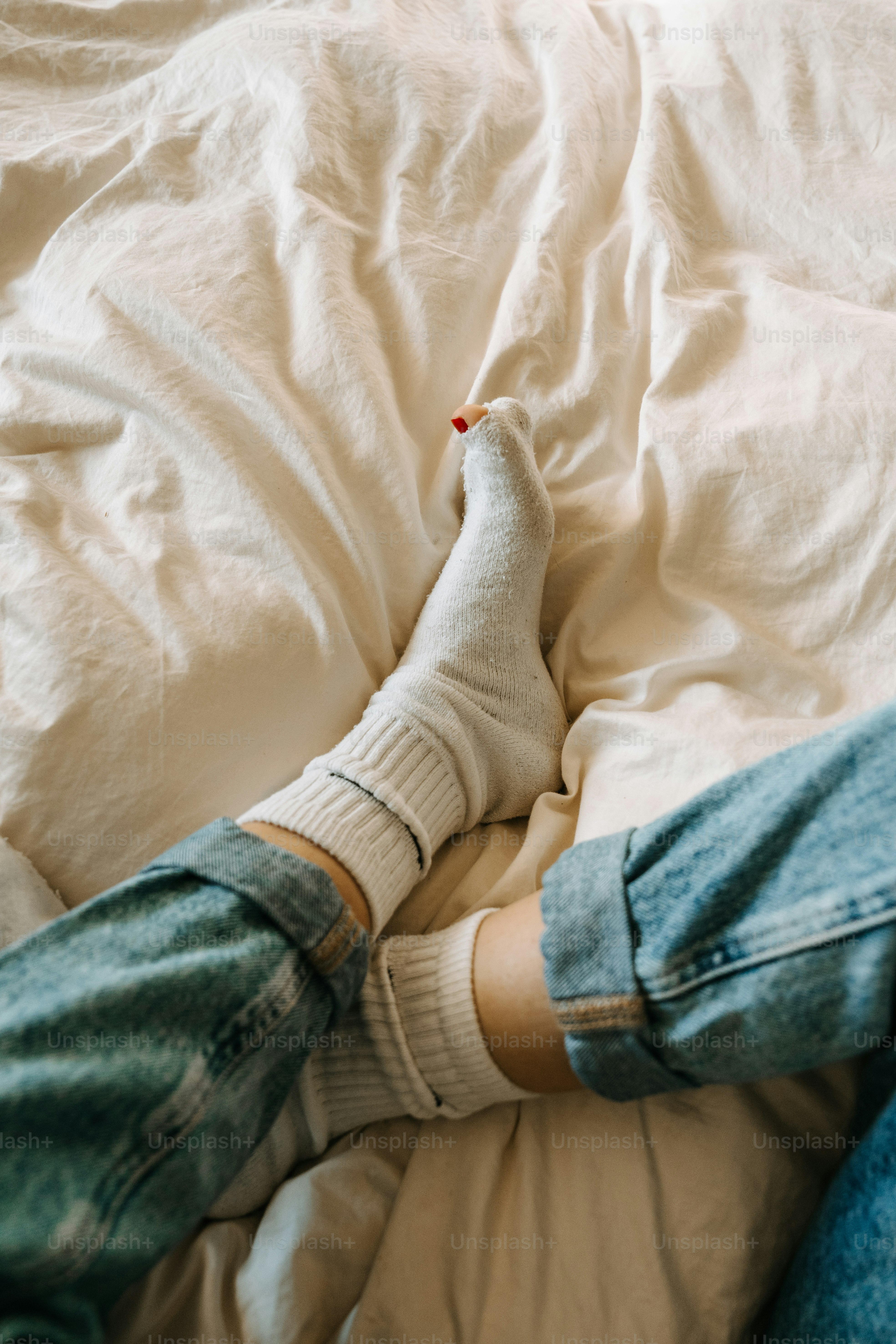 A person laying on a bed with their feet up