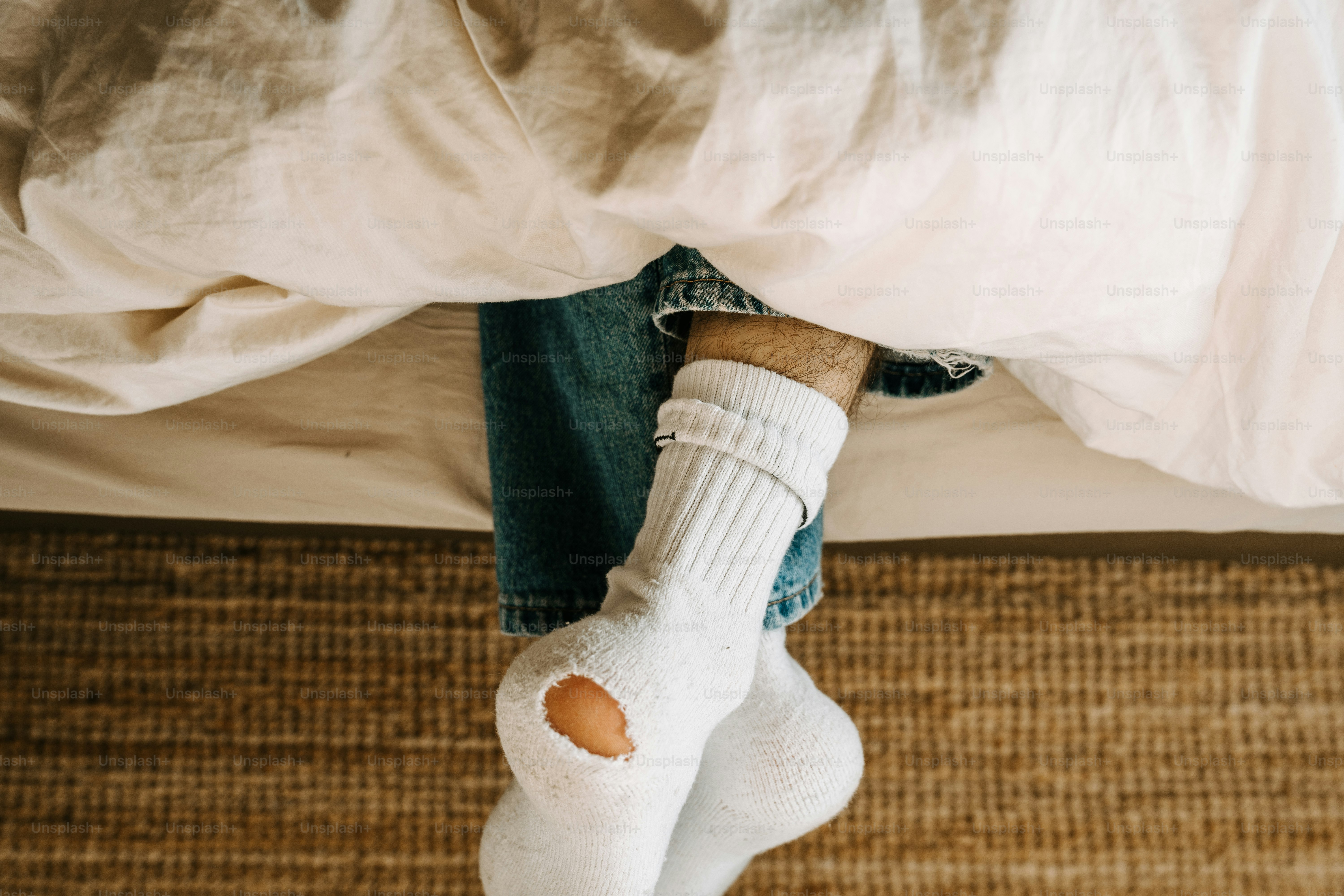 A person laying in bed with their feet on a pillow