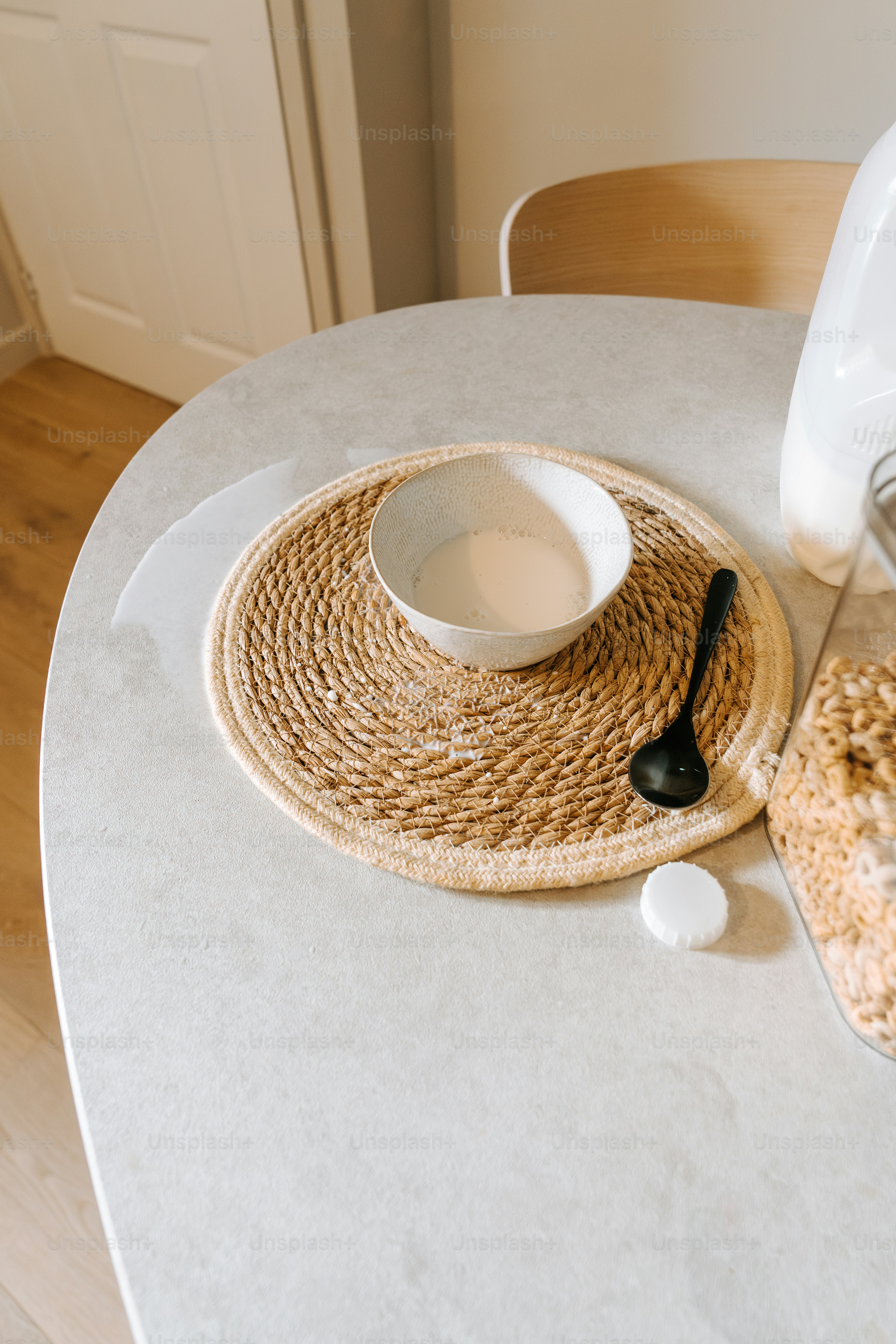 A table topped with a bowl of cereal and a milk jug