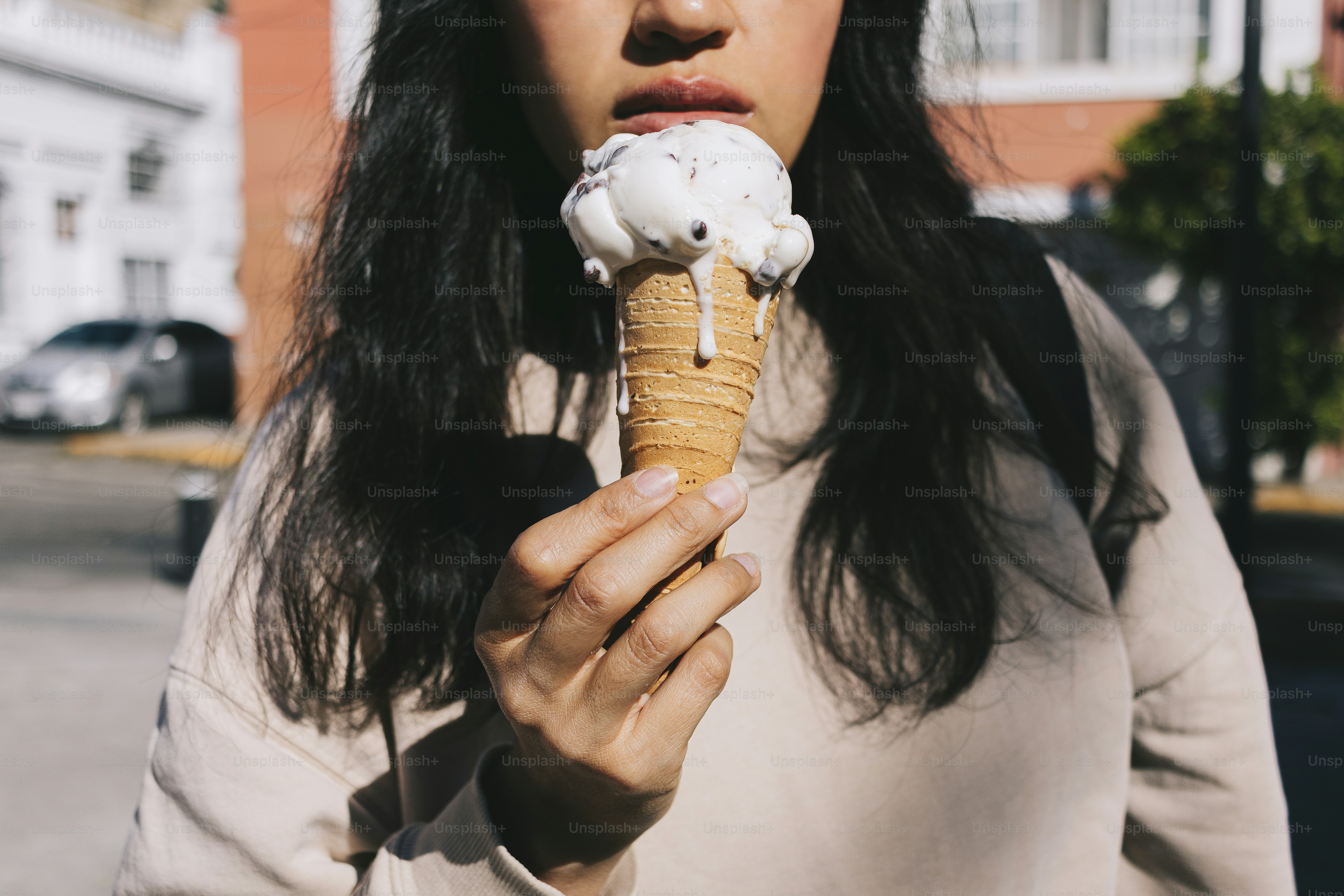 A woman eating an ice cream cone on the street