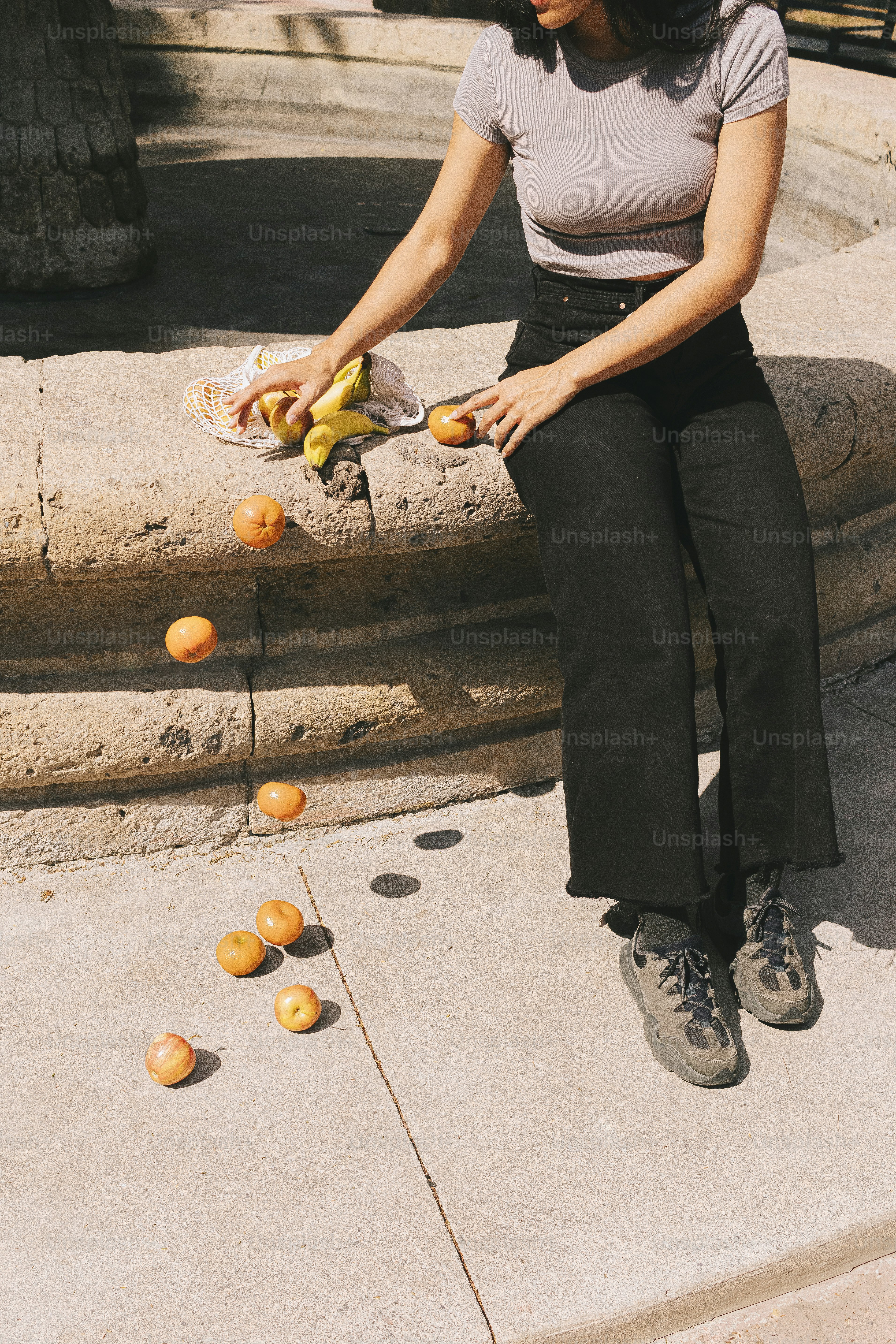 オレンジの束を持って棚に座っている女性