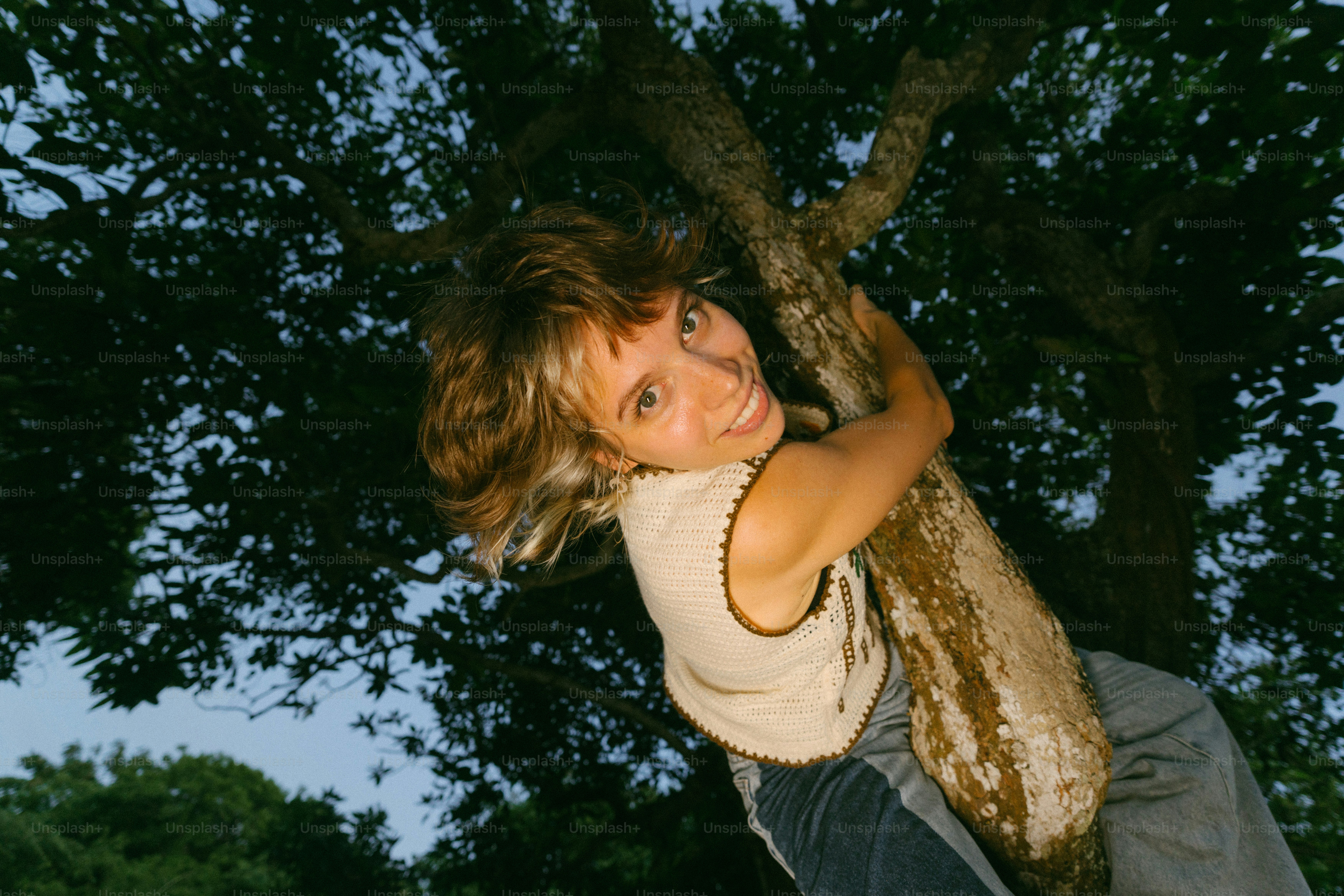 A young girl is holding onto a tree