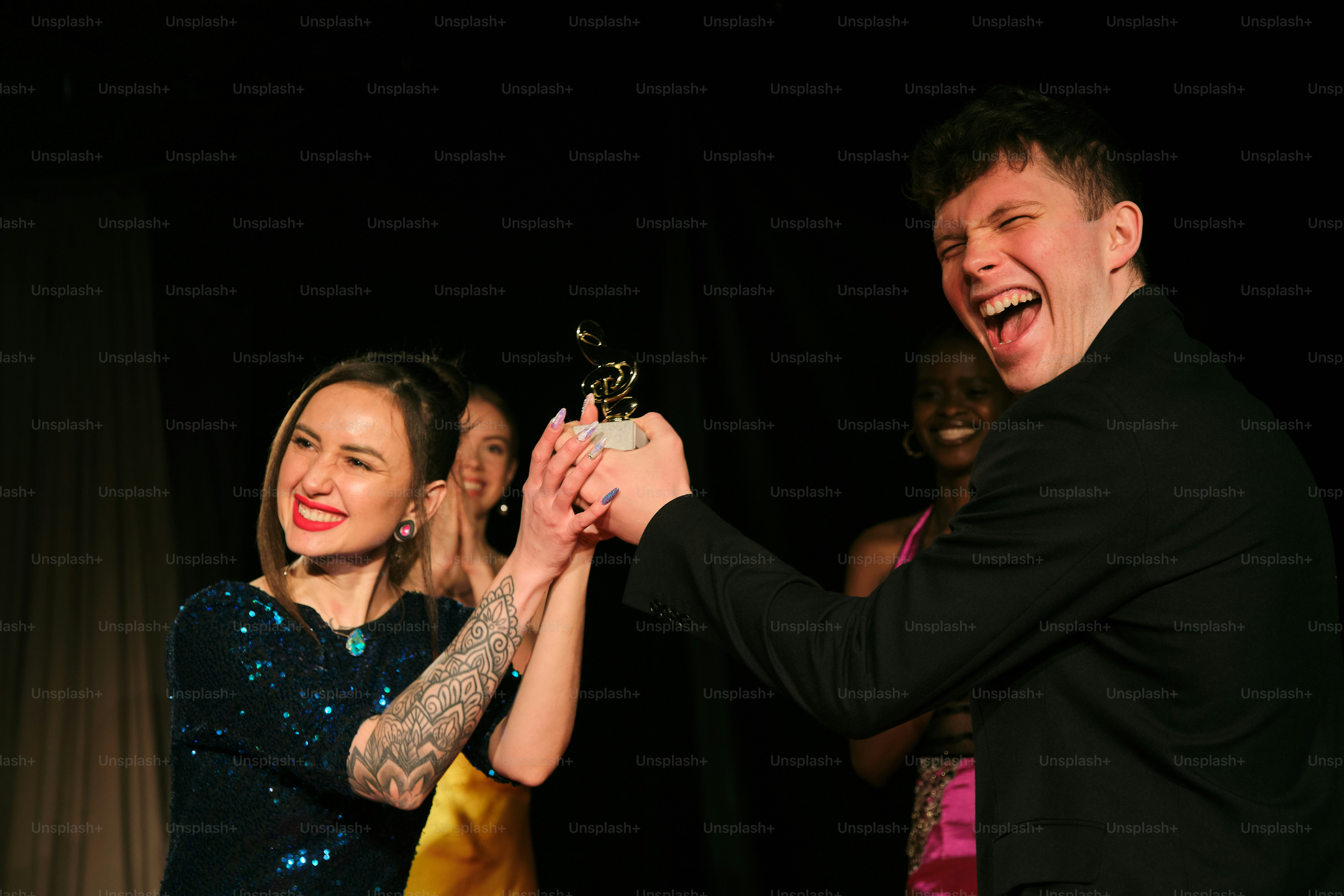 A man holding a woman's hand while she holds a trophy