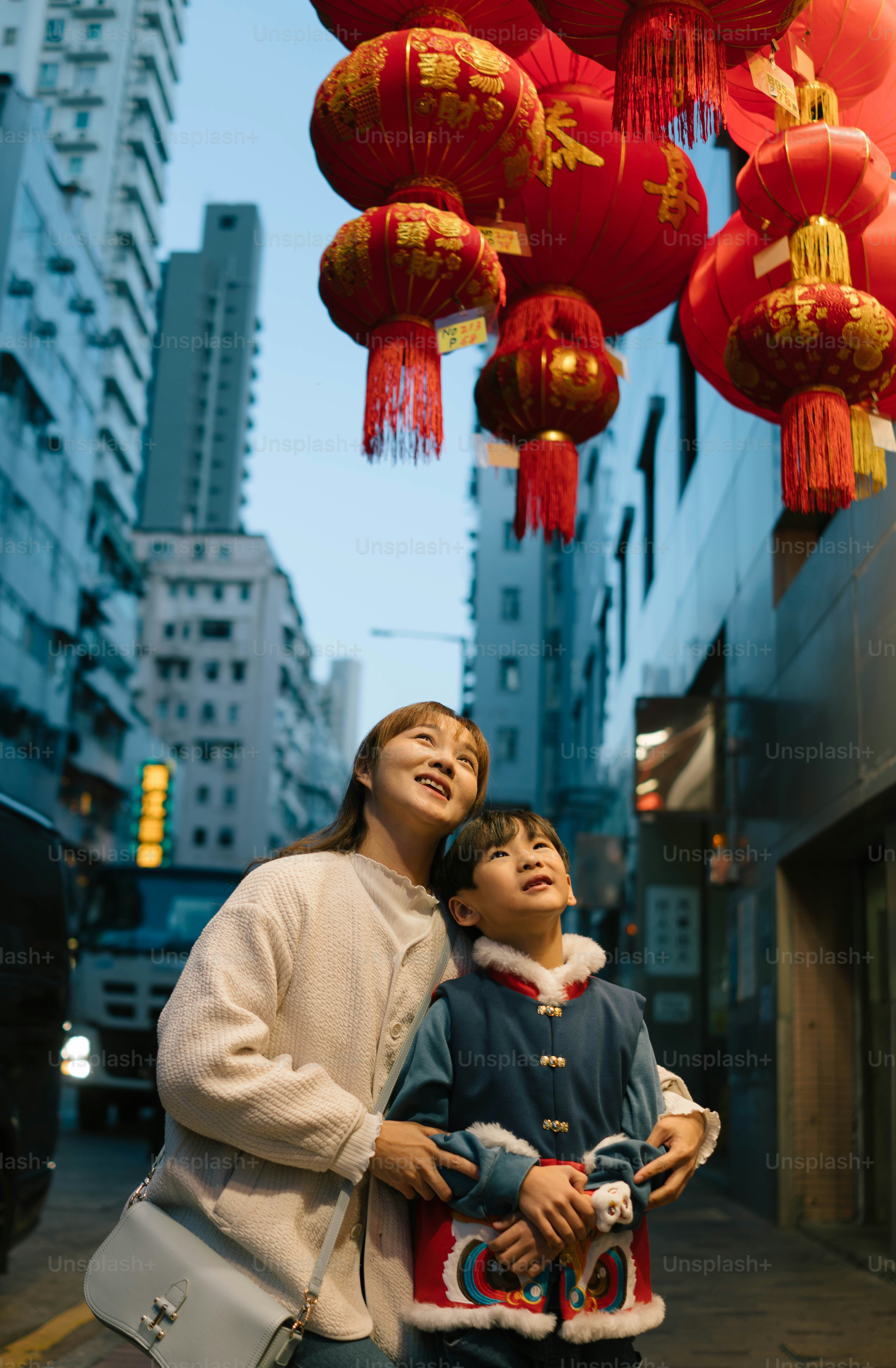 A woman standing next to a child under red lanterns