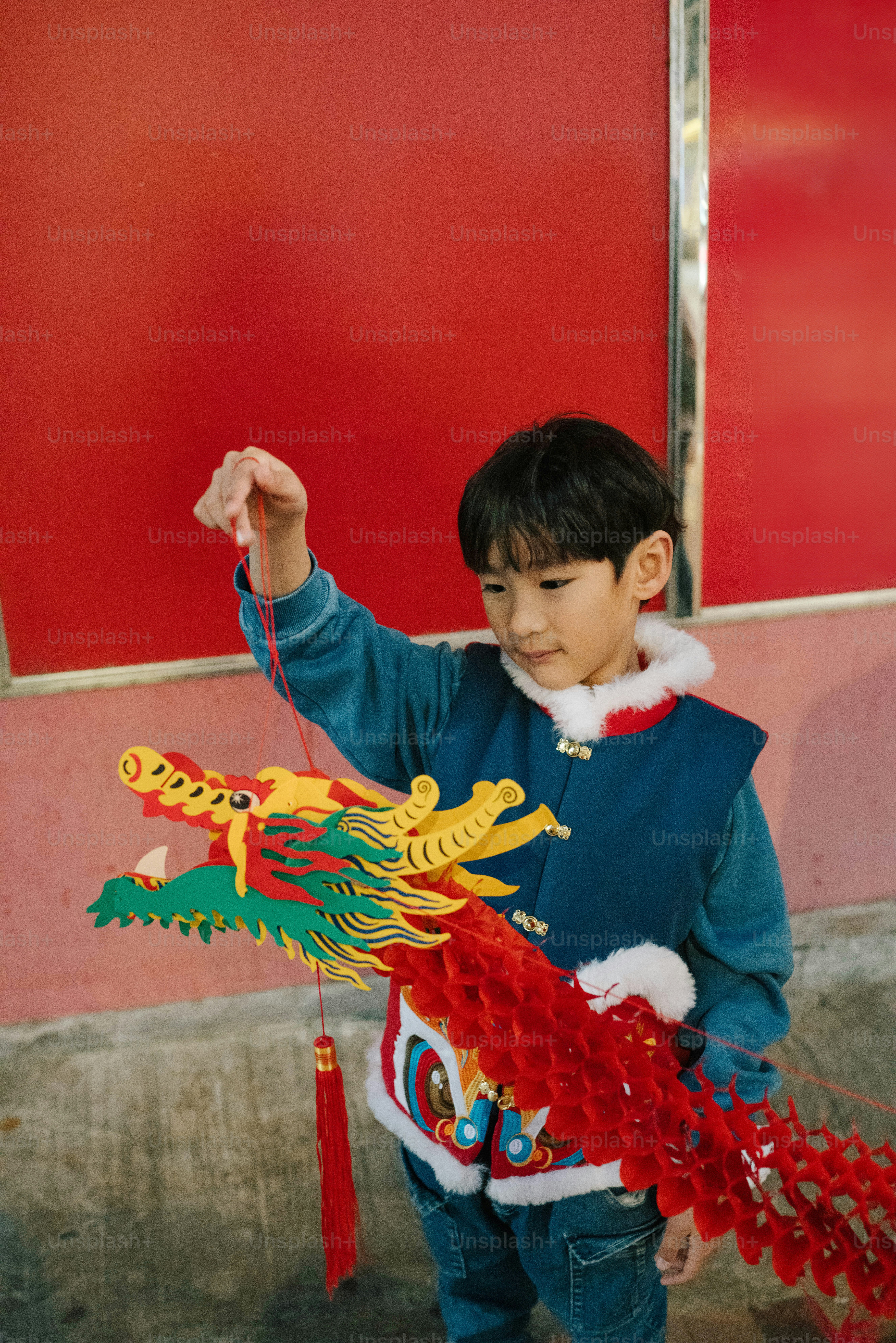 A young boy is holding a dragon kite