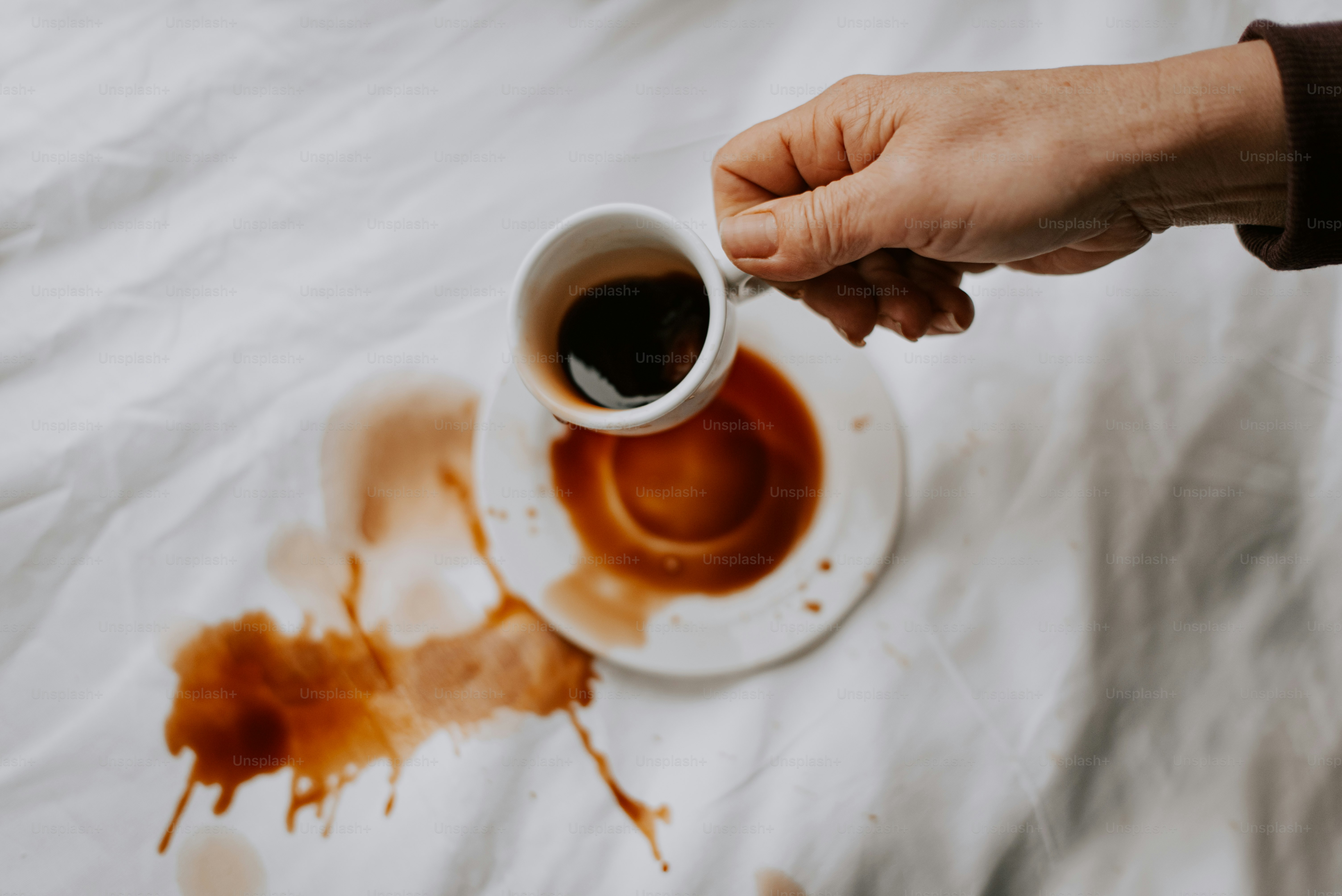Une personne tenant une tasse de café sur un lit
