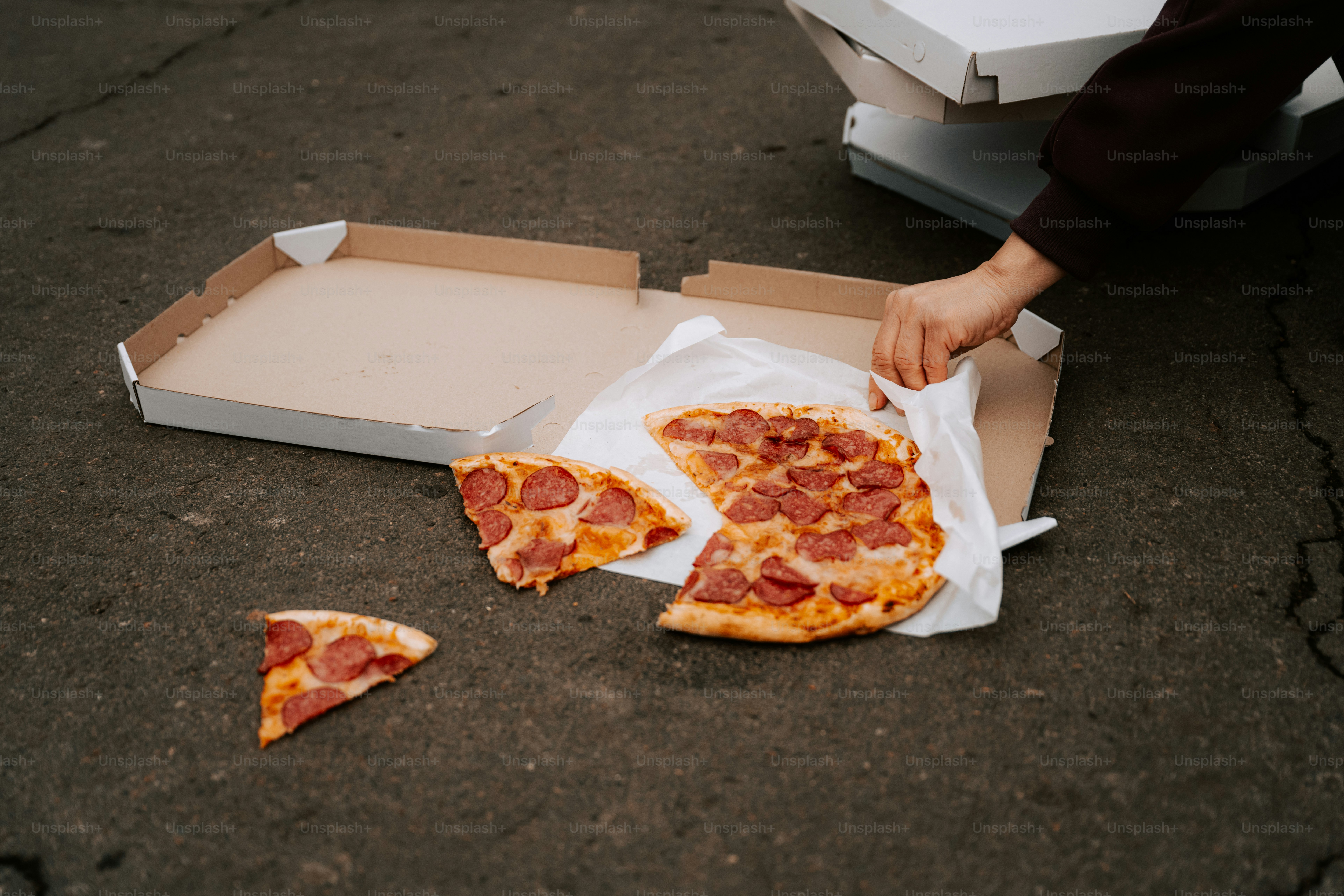 Une personne ramassant des tranches de pizza dans une boîte