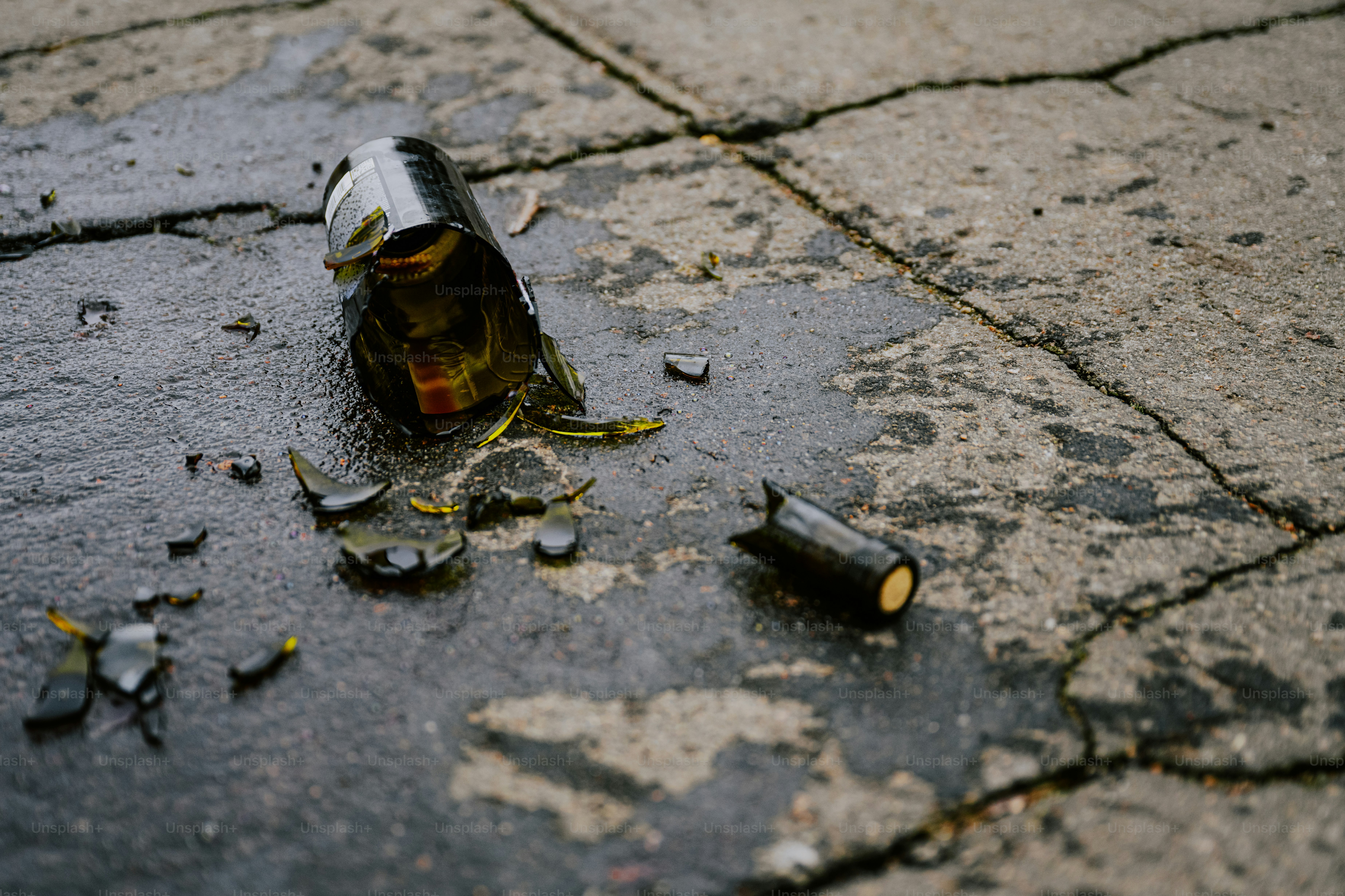 A can of beer sitting on the ground next to a broken bottle