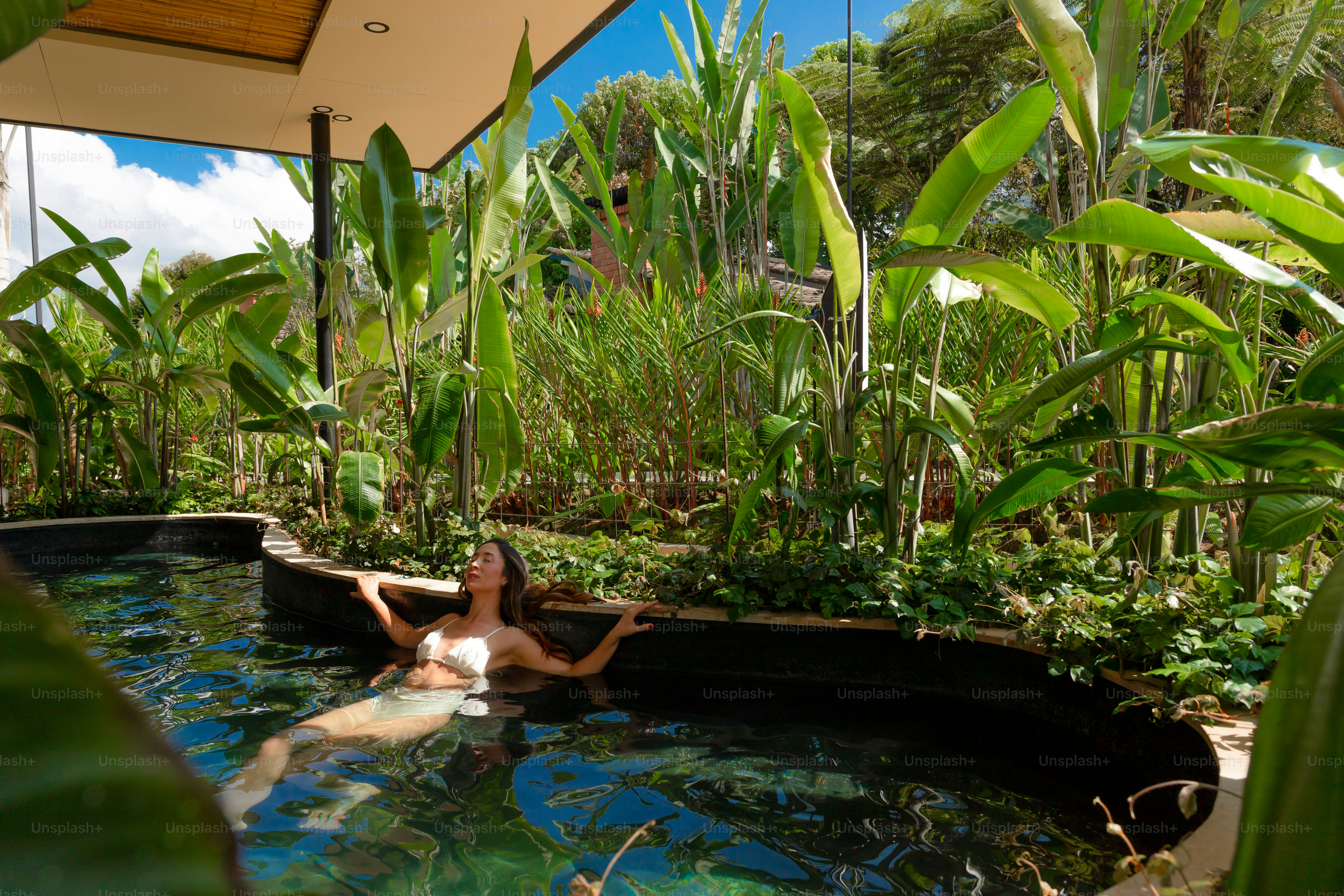 A woman laying in a pool of water surrounded by greenery