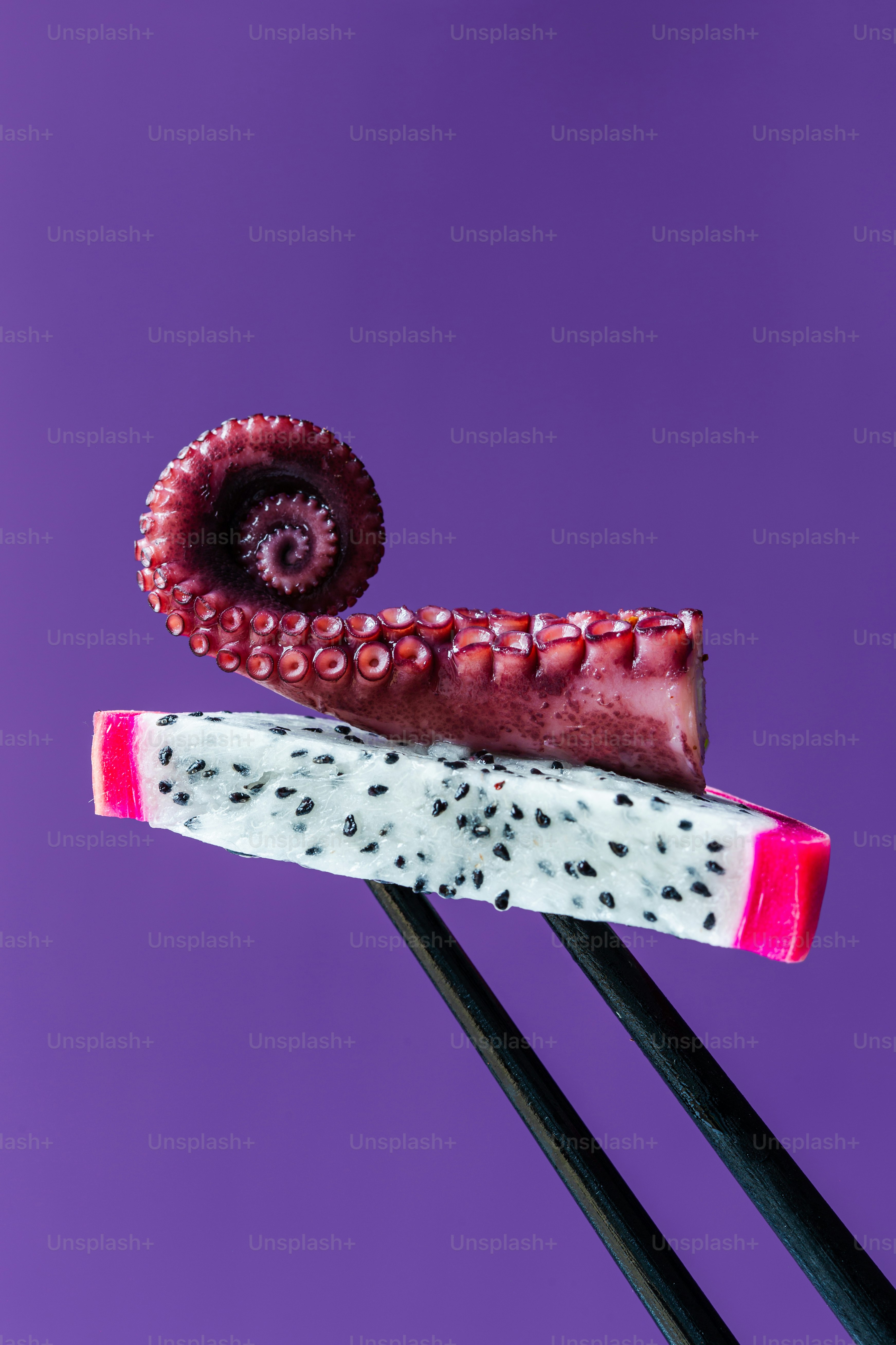 Un fondo morado con una pieza de fruta y dos palillos