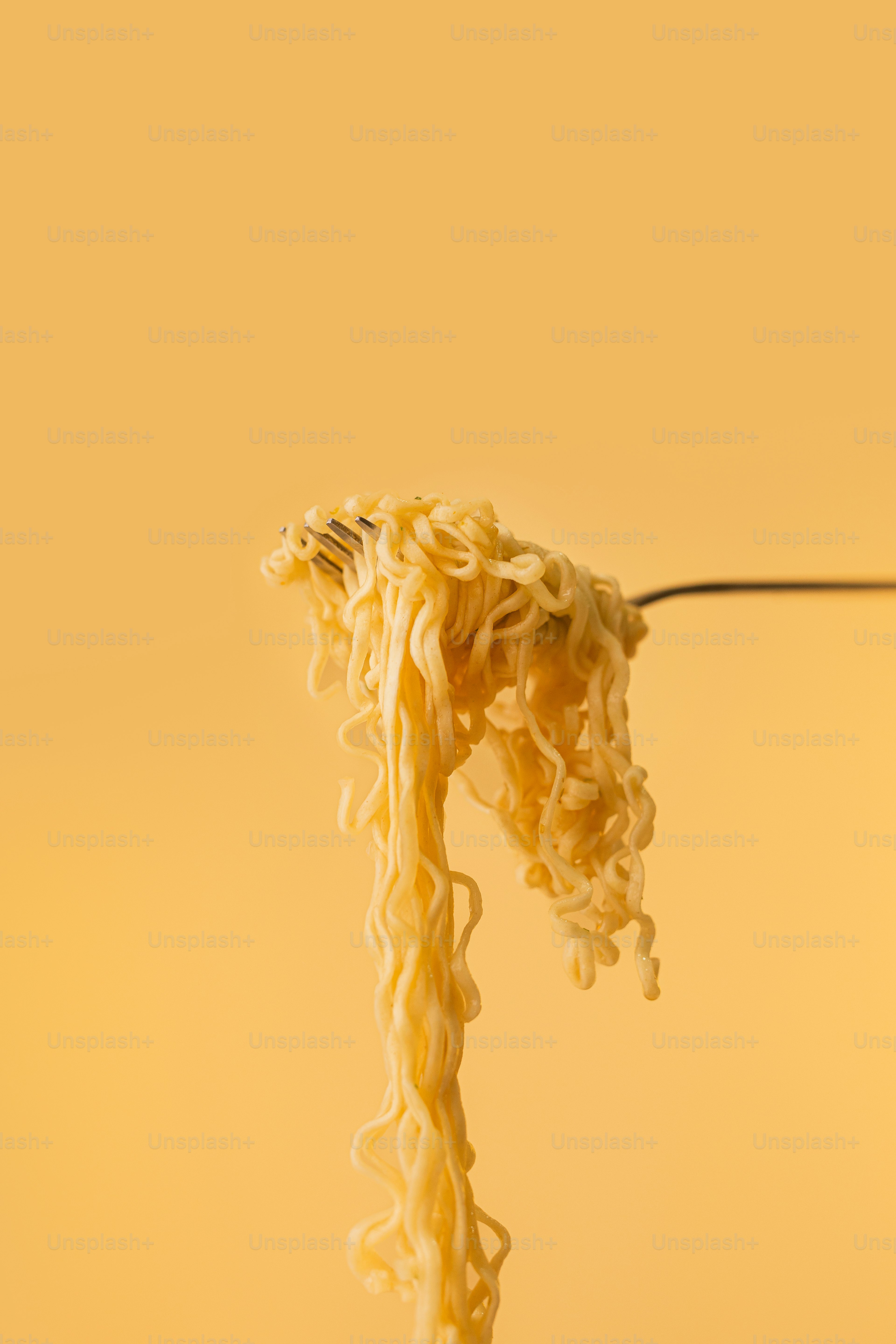 A fork full of noodles being lifted from a bowl