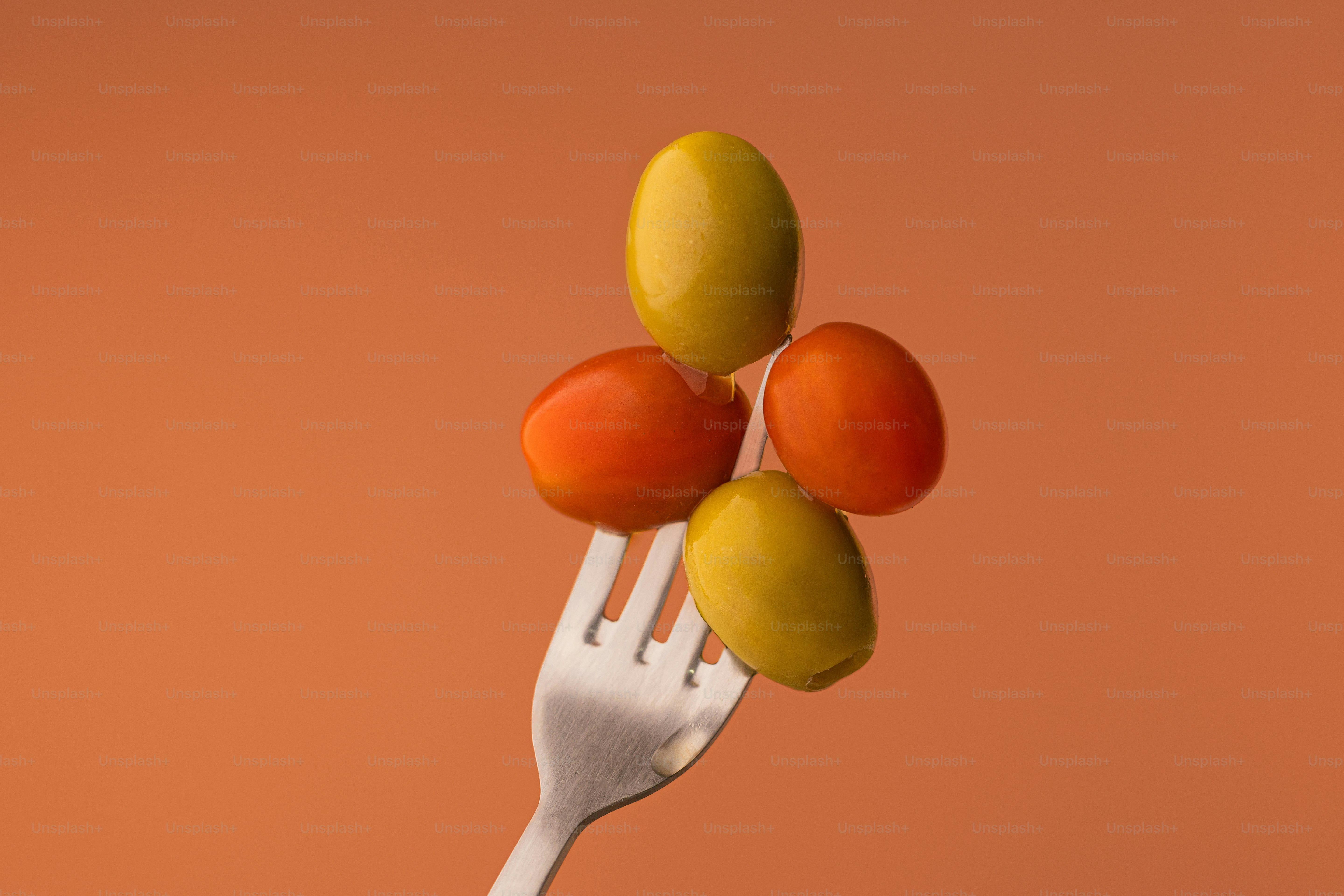 Eine Gabel mit drei Tomaten und zwei Oliven darauf