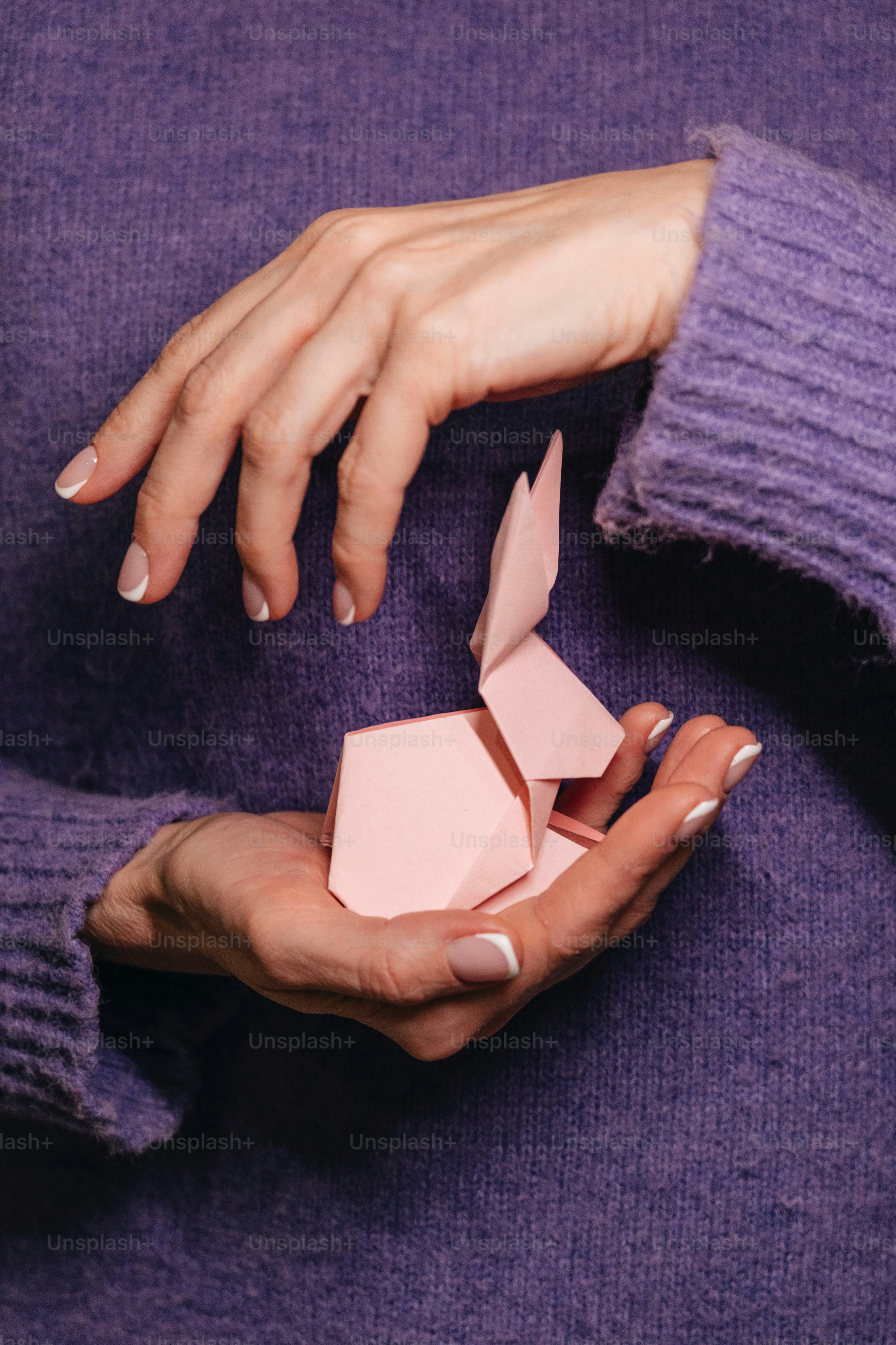 A woman holding a pink origami object in her hands