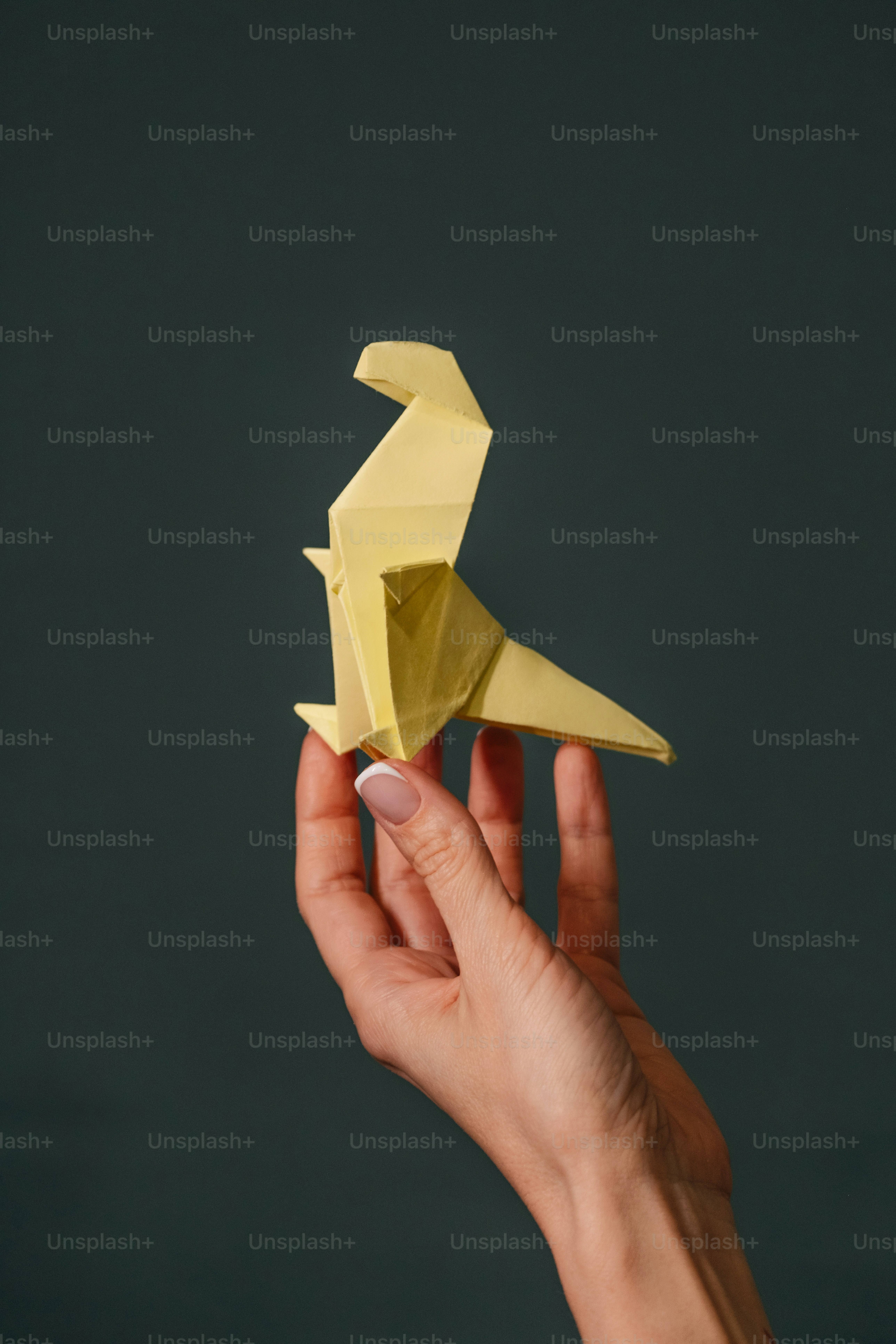 A hand holding a yellow origami bird