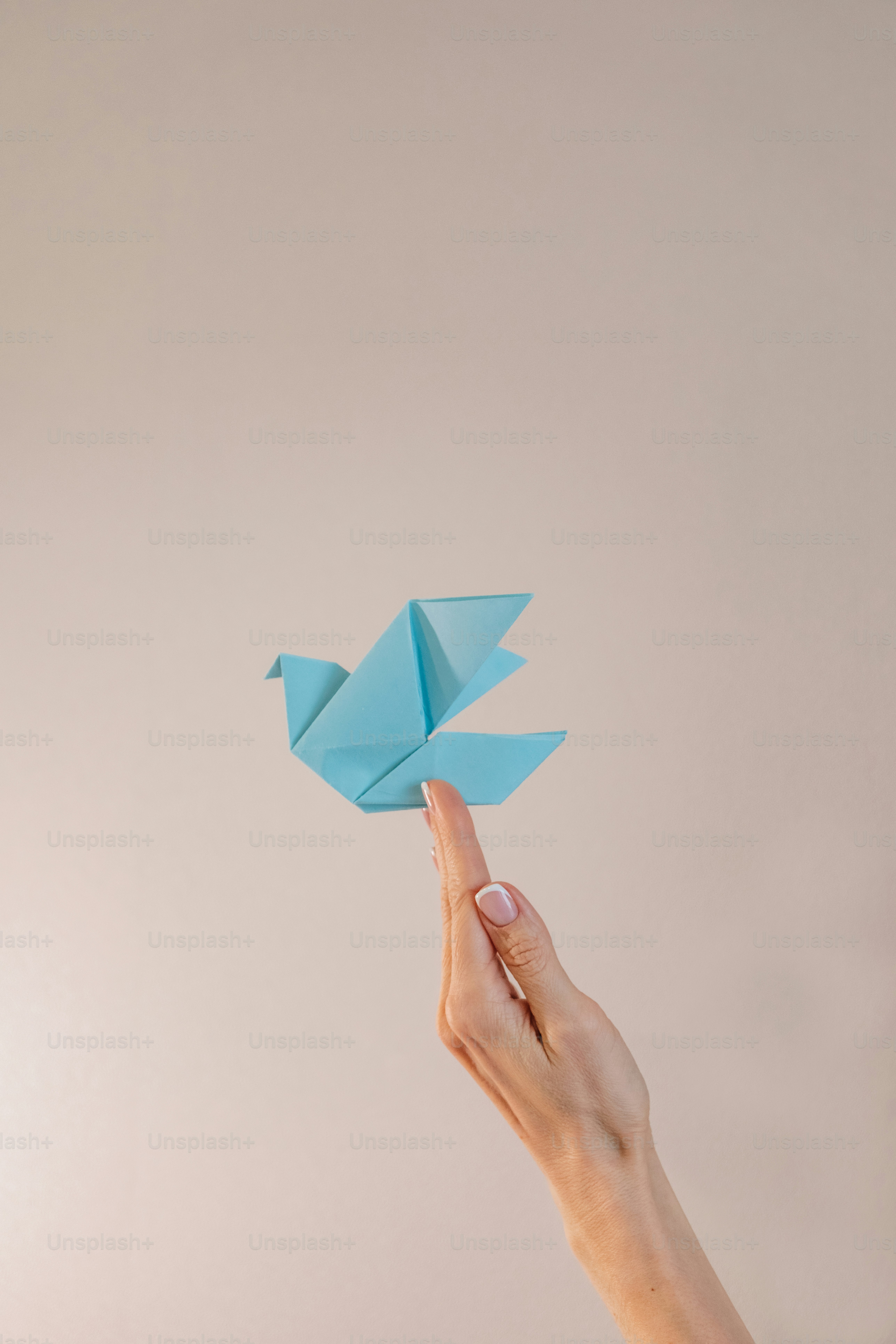 A hand holding a blue origami bird