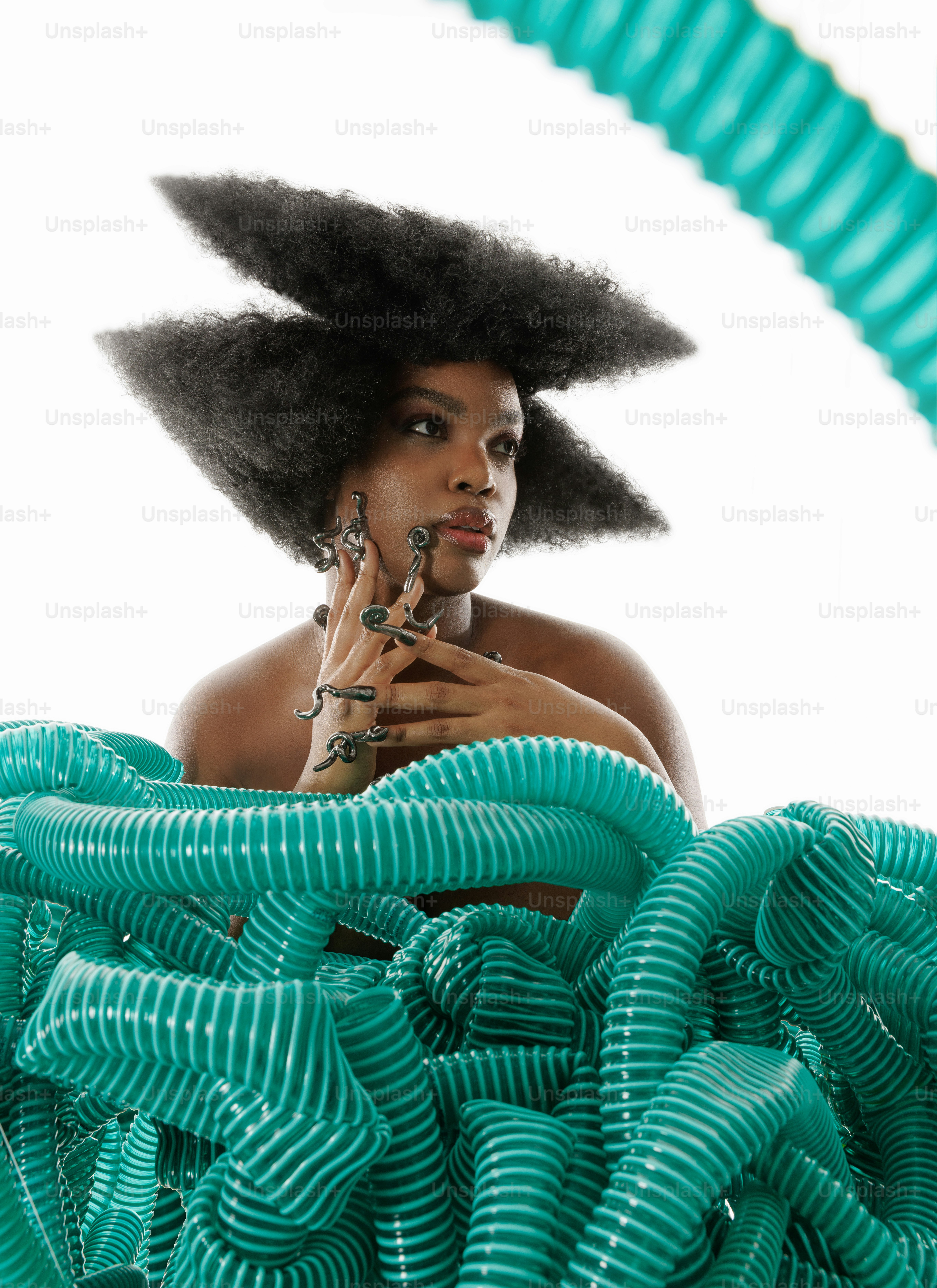 A woman with an afro standing in front of a pile of green hoses