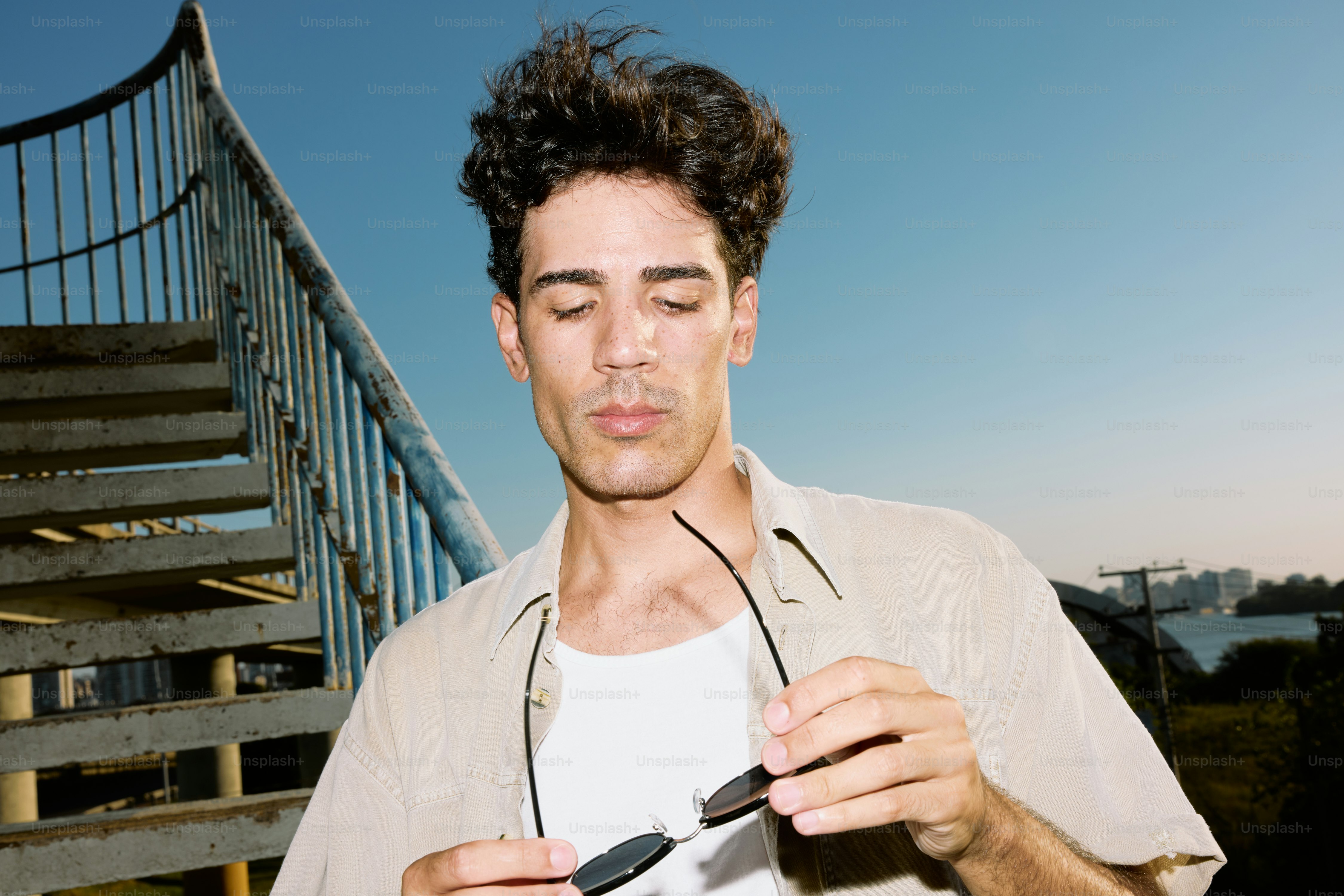 A man holding a pair of headphones in front of a stair case