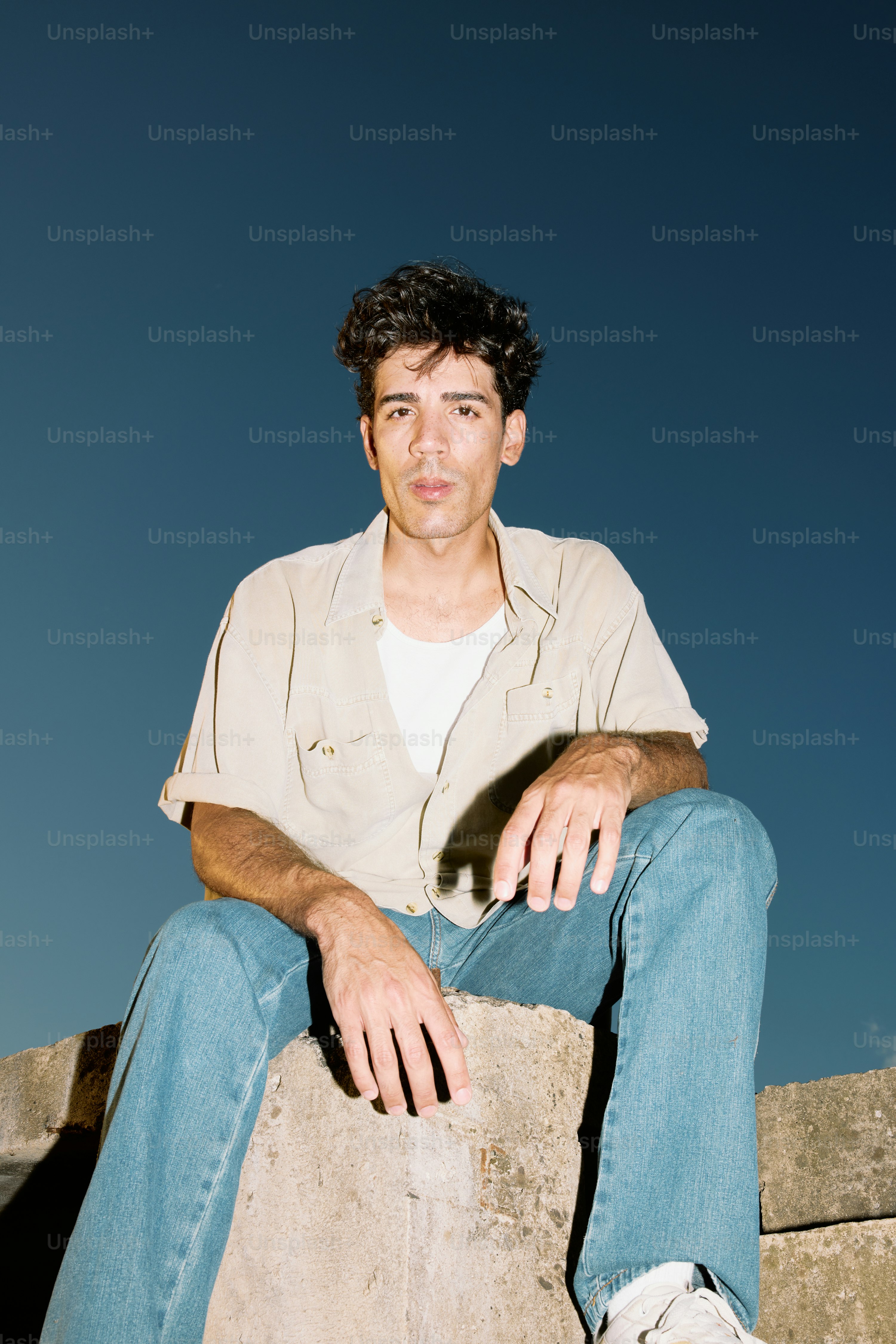 A man sitting on top of a stone wall