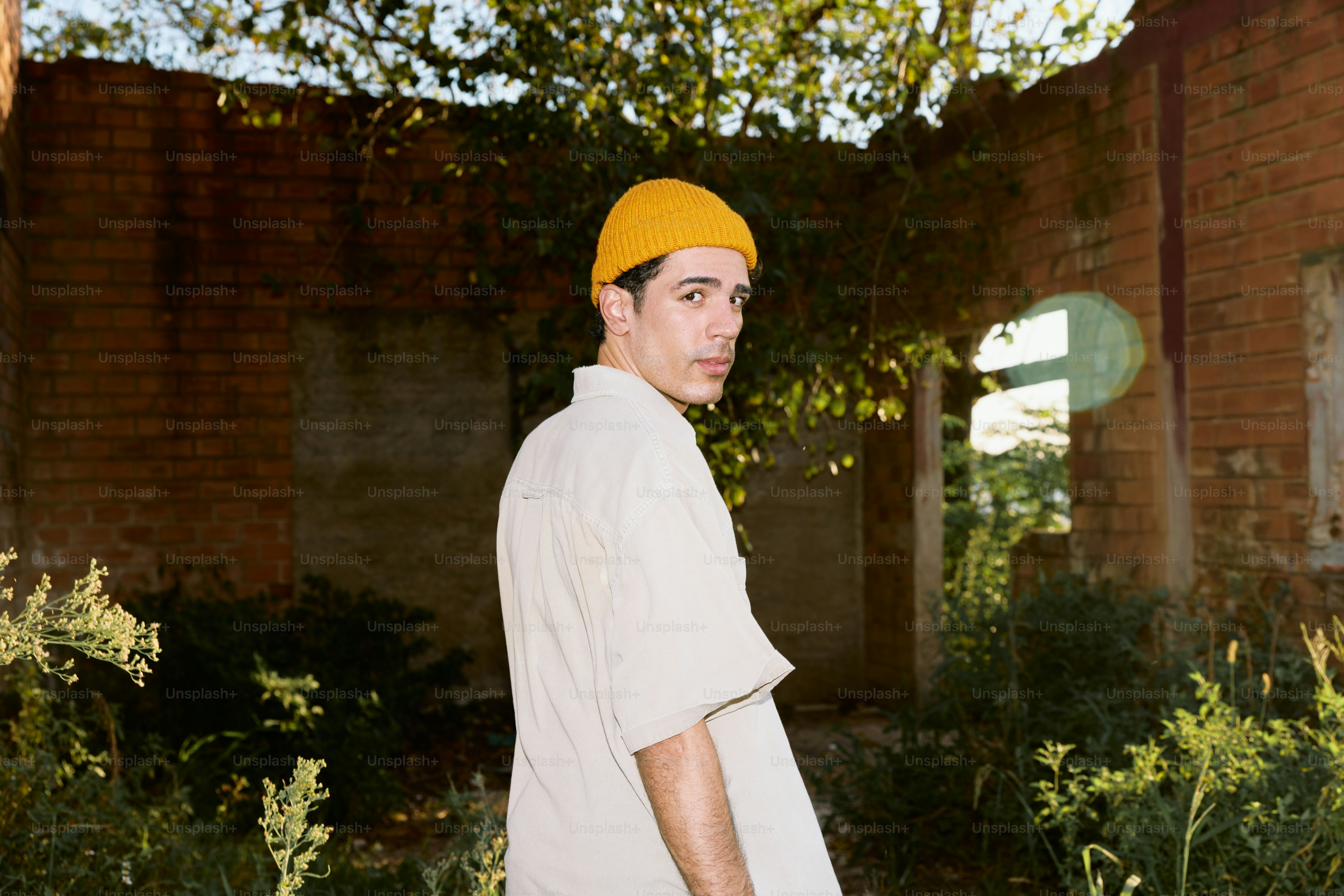 A young man wearing a yellow hat standing in front of a building