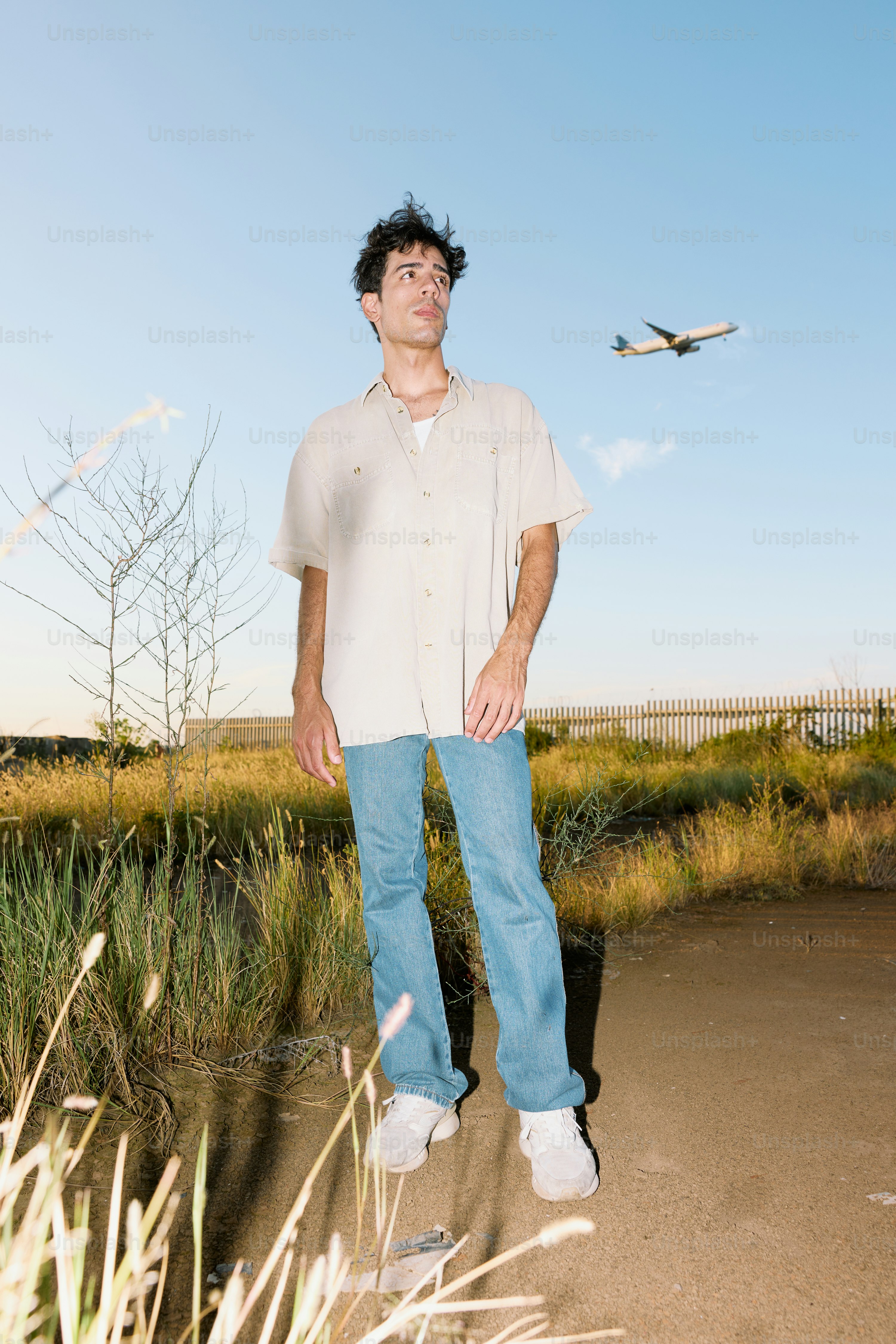 비행기를 배경으로 들판에 서 있는 남자