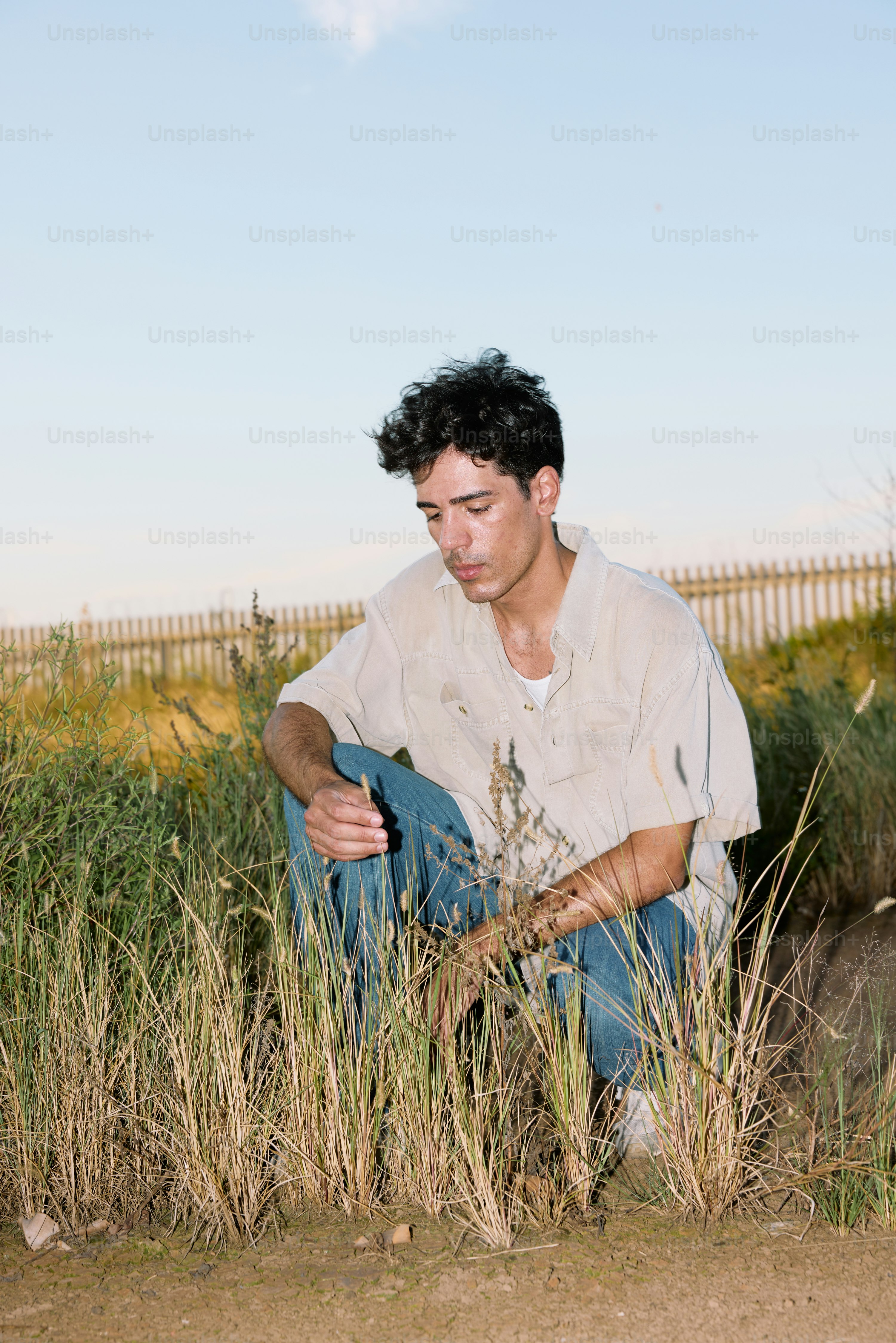 A man sitting in a field of tall grass photo – Portrait Image on Unsplash