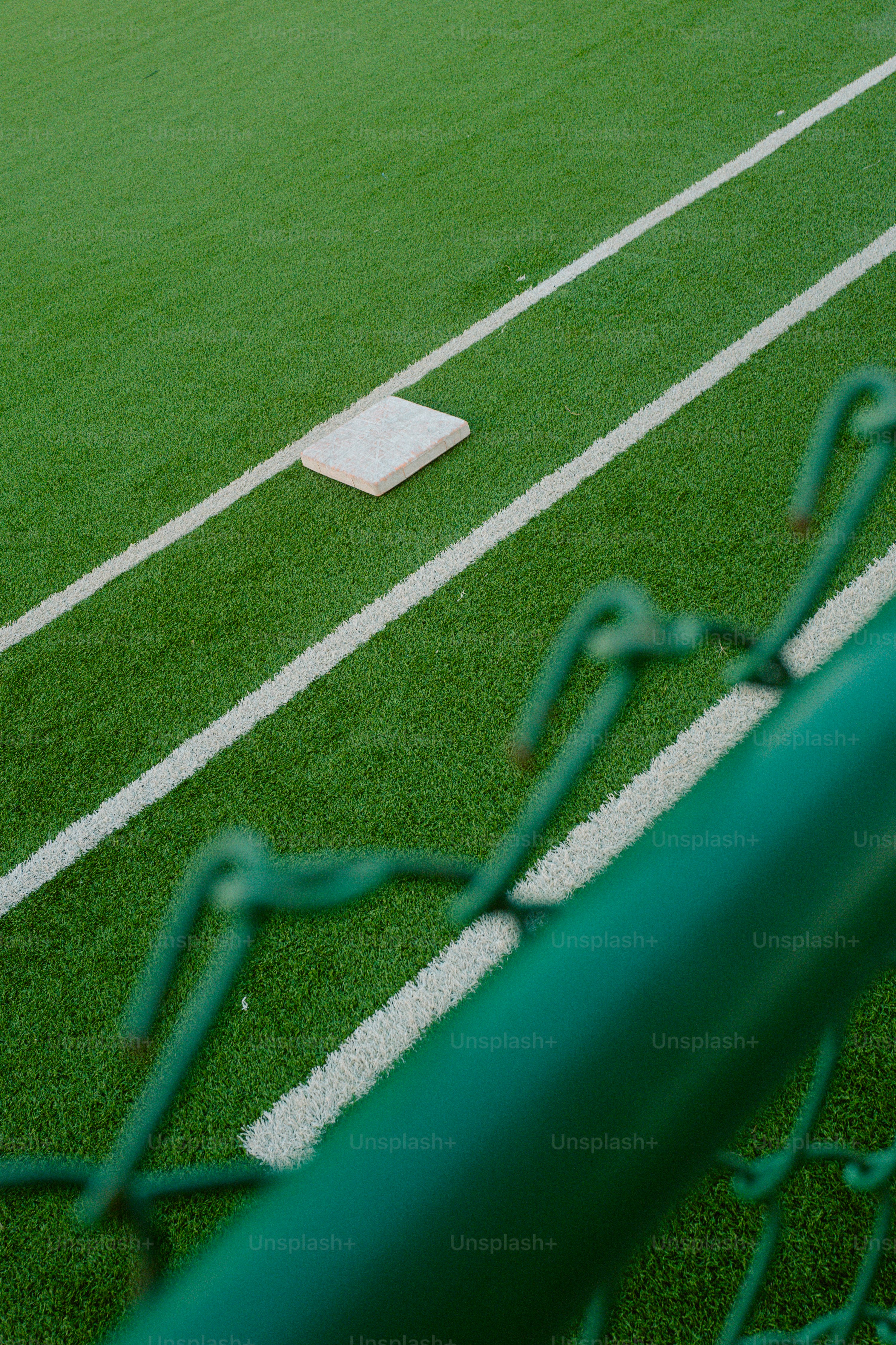 A baseball field with a green fence and a white base ball