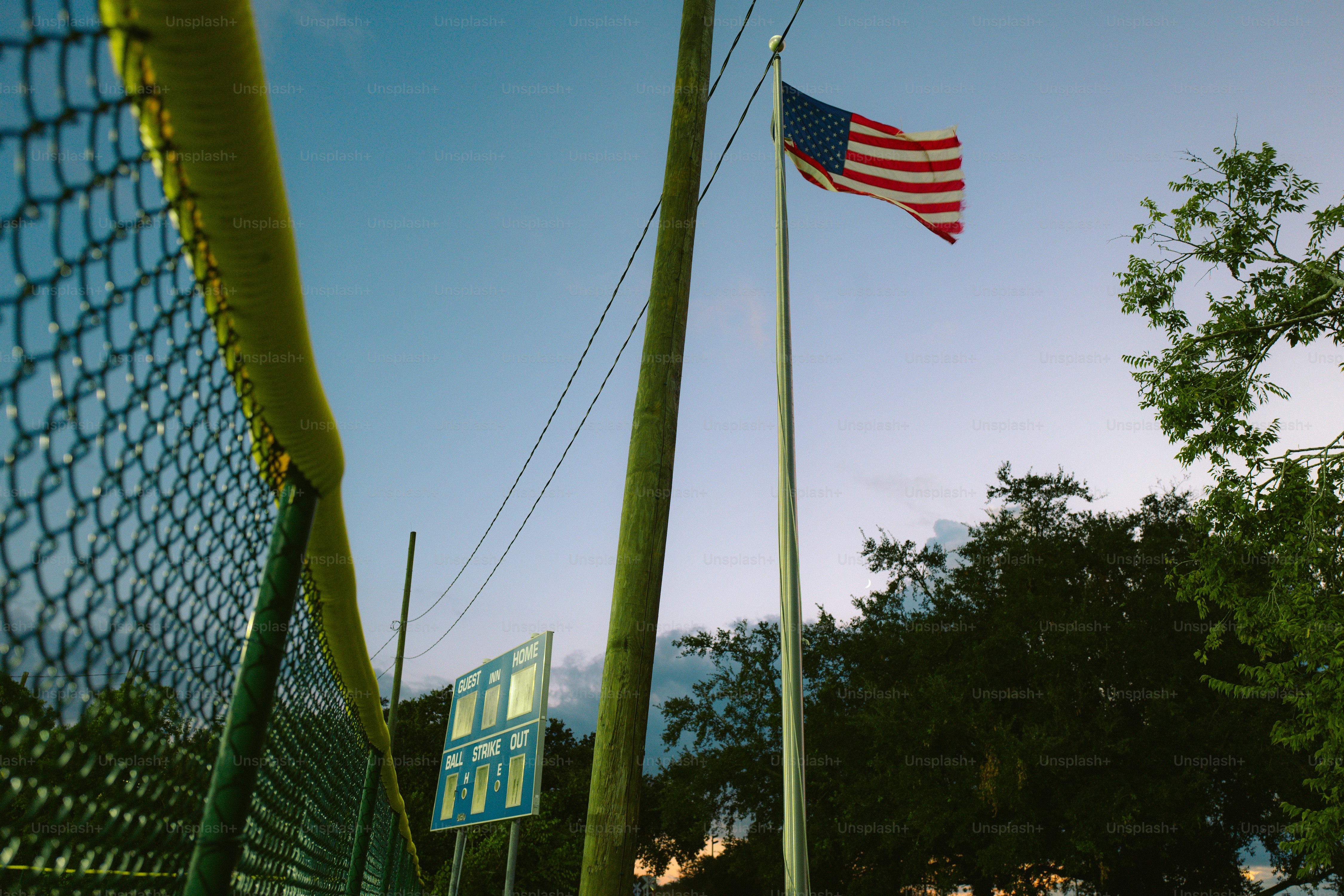 An american flag flying next to a green fence
