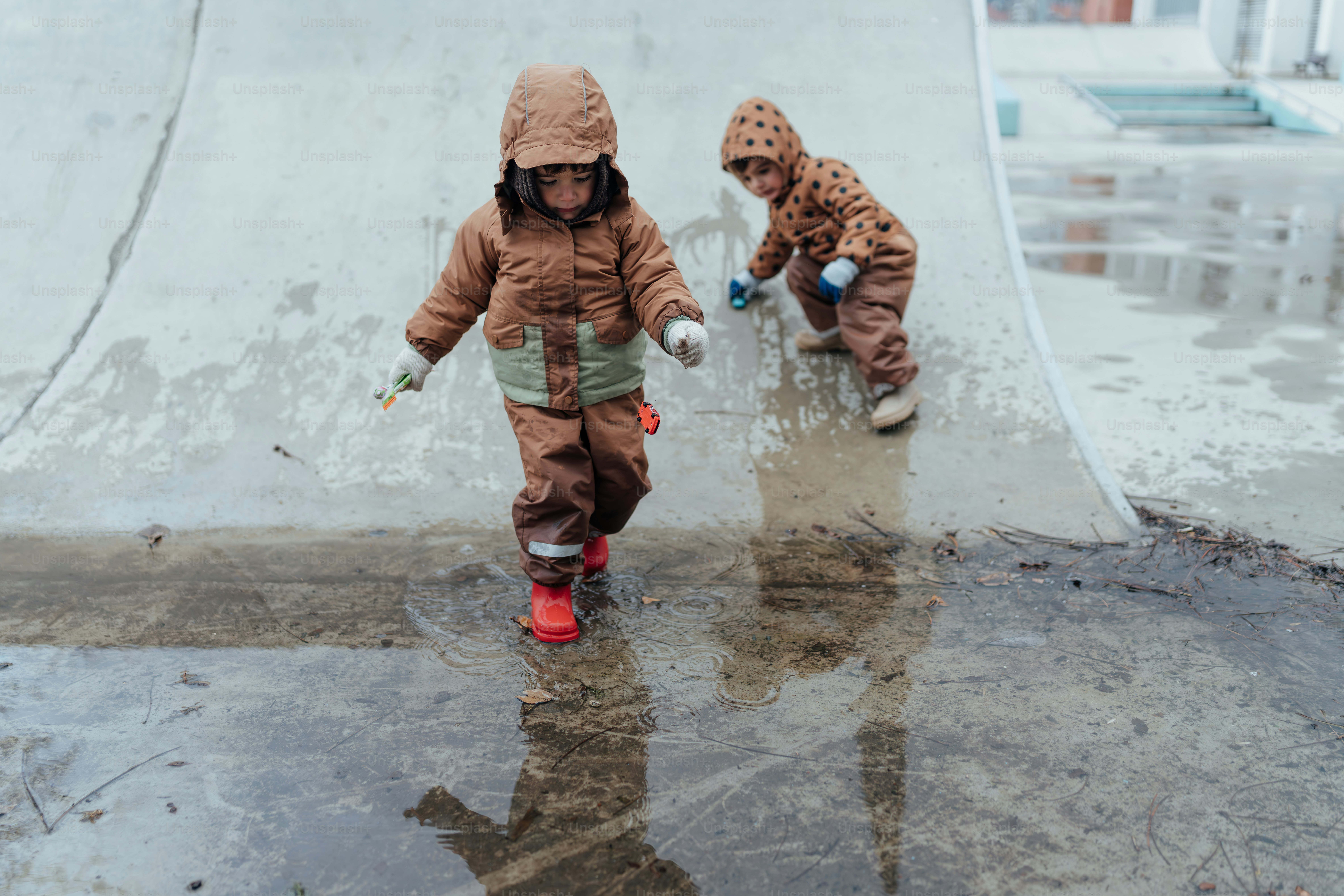 Un par de niños que están parados bajo la lluvia