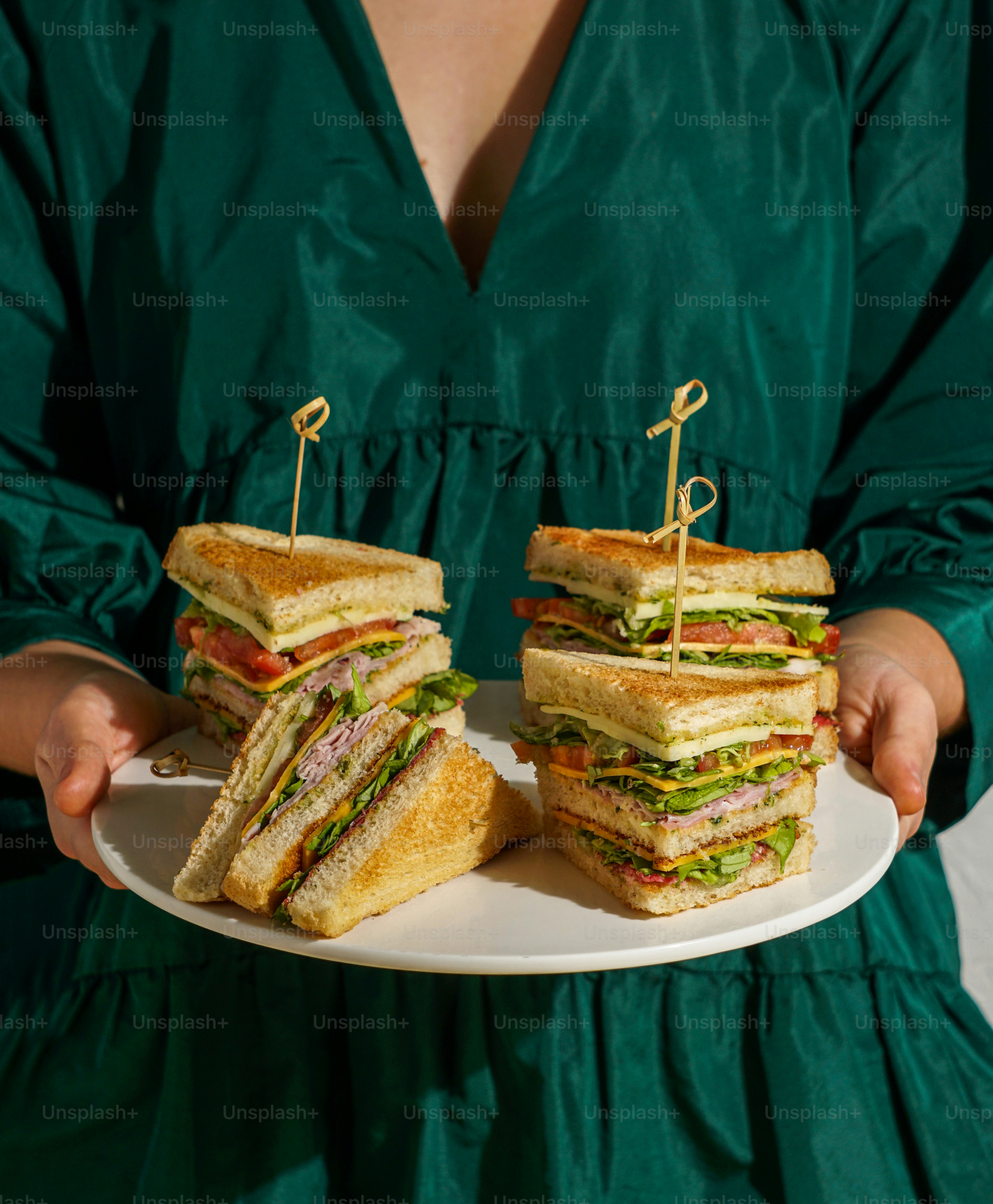A woman in a green dress holding a plate of sandwiches