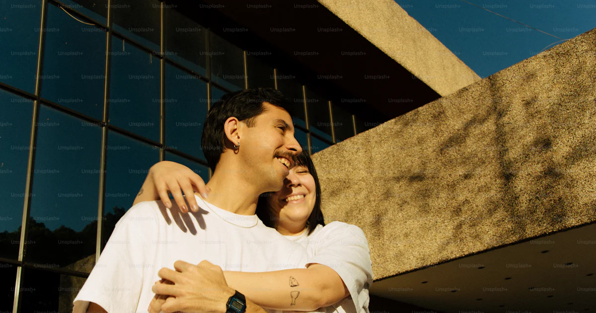 Couple hugs in front of a modern building. photo – Love Image on Unsplash