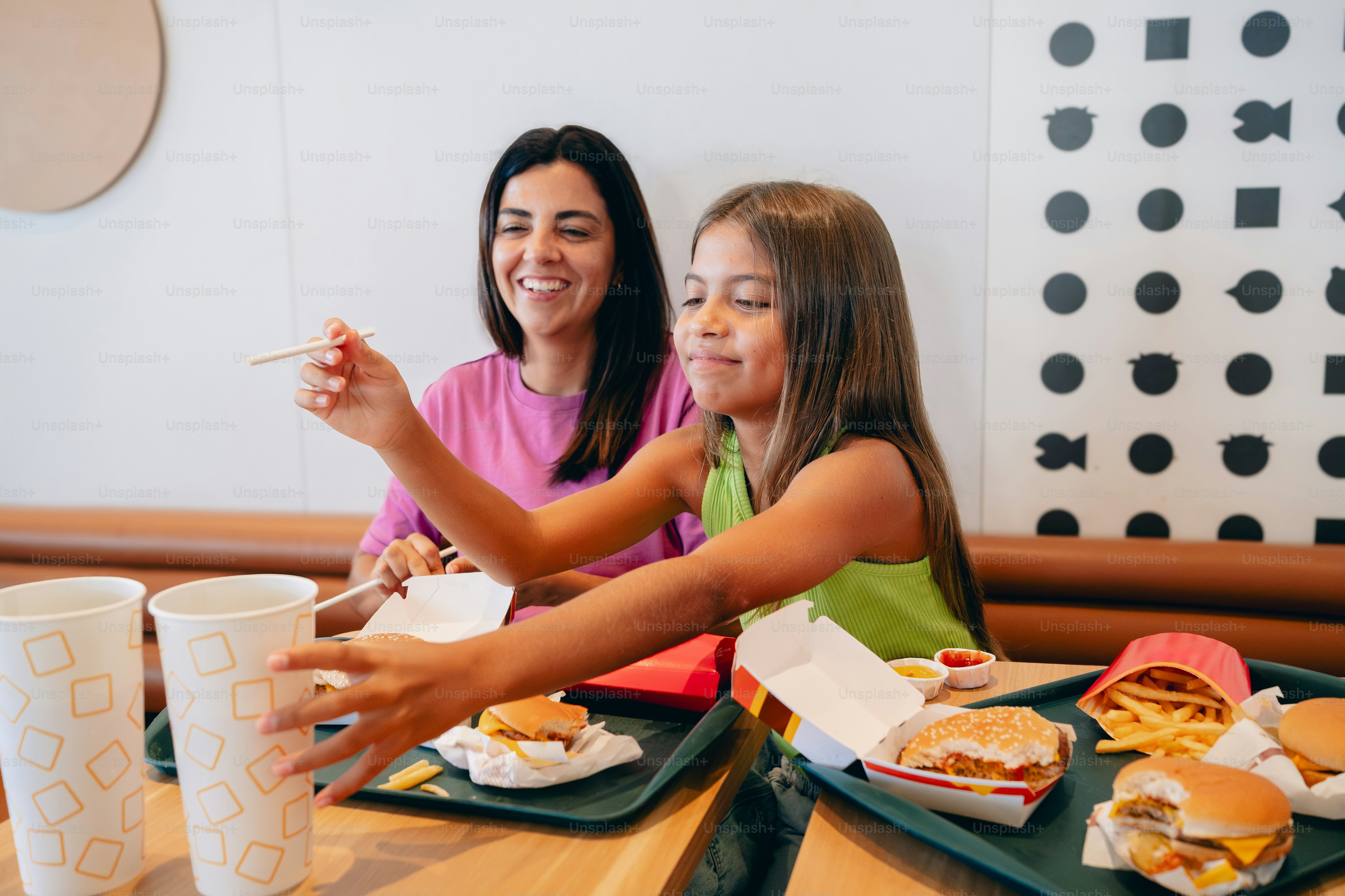 A woman and a little girl sitting at a table with plates of food