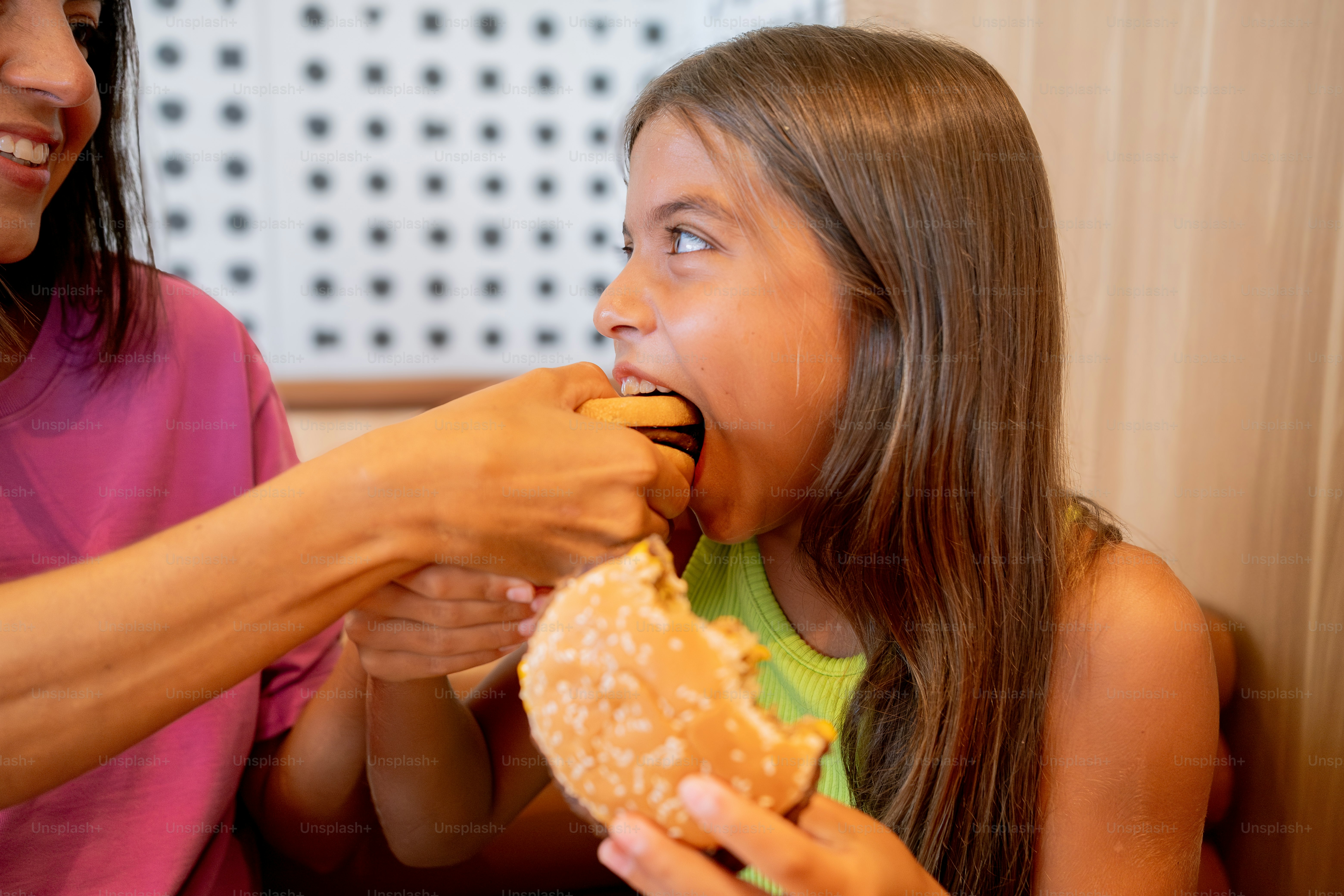 A woman feeding a little girl a donut