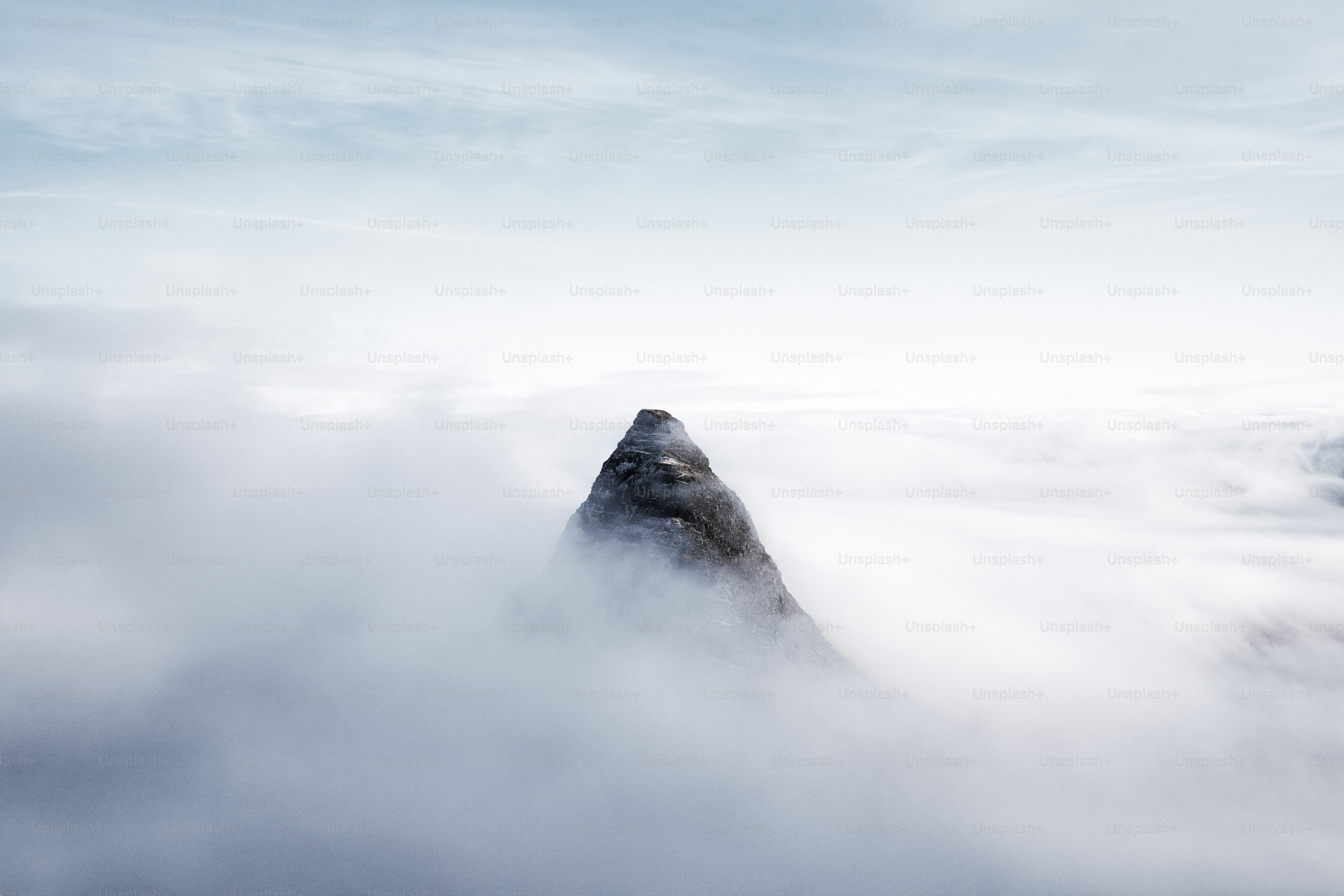 A mountain in the middle of a cloud filled sky
