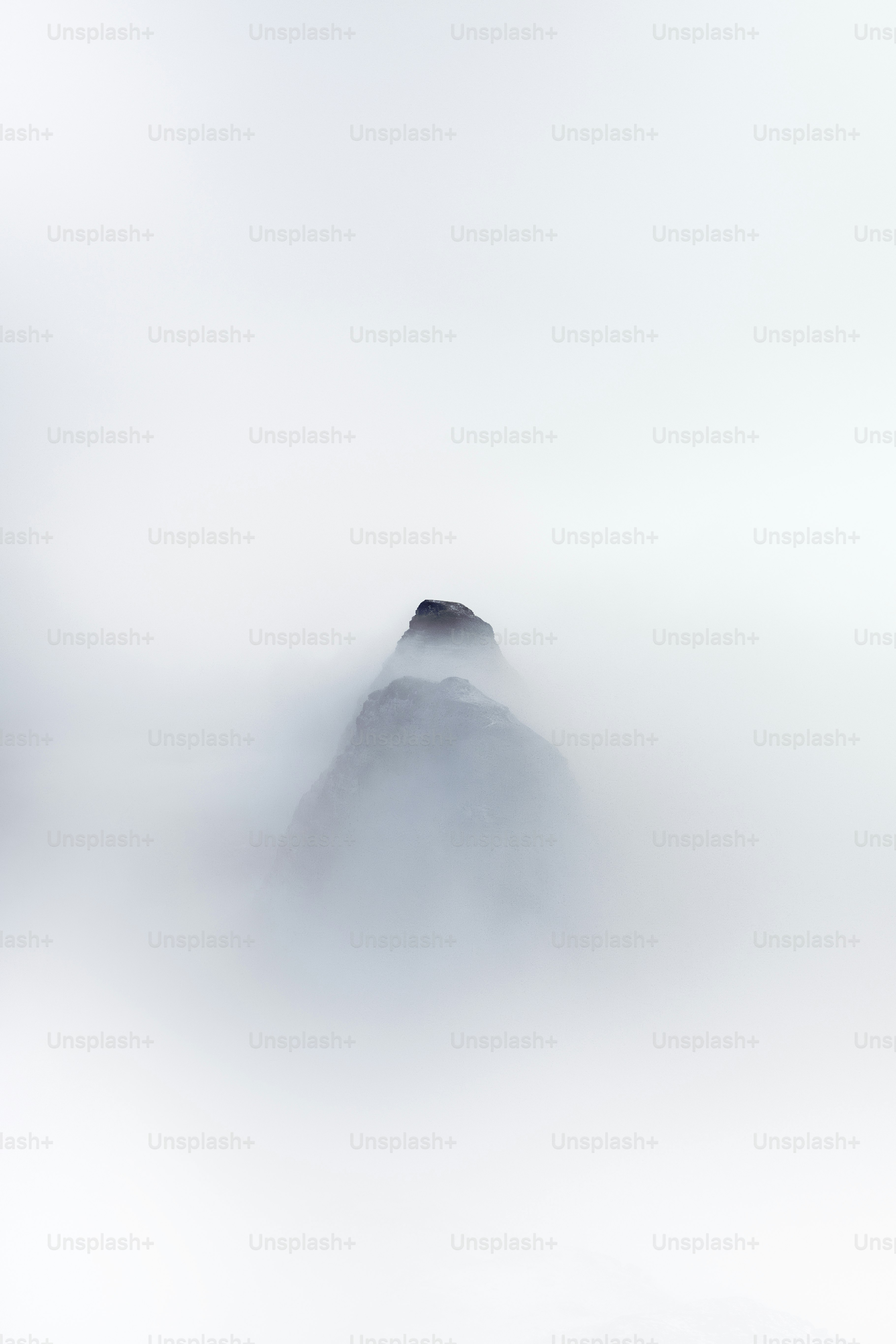 A foggy mountain with a single rock sticking out of the fog
