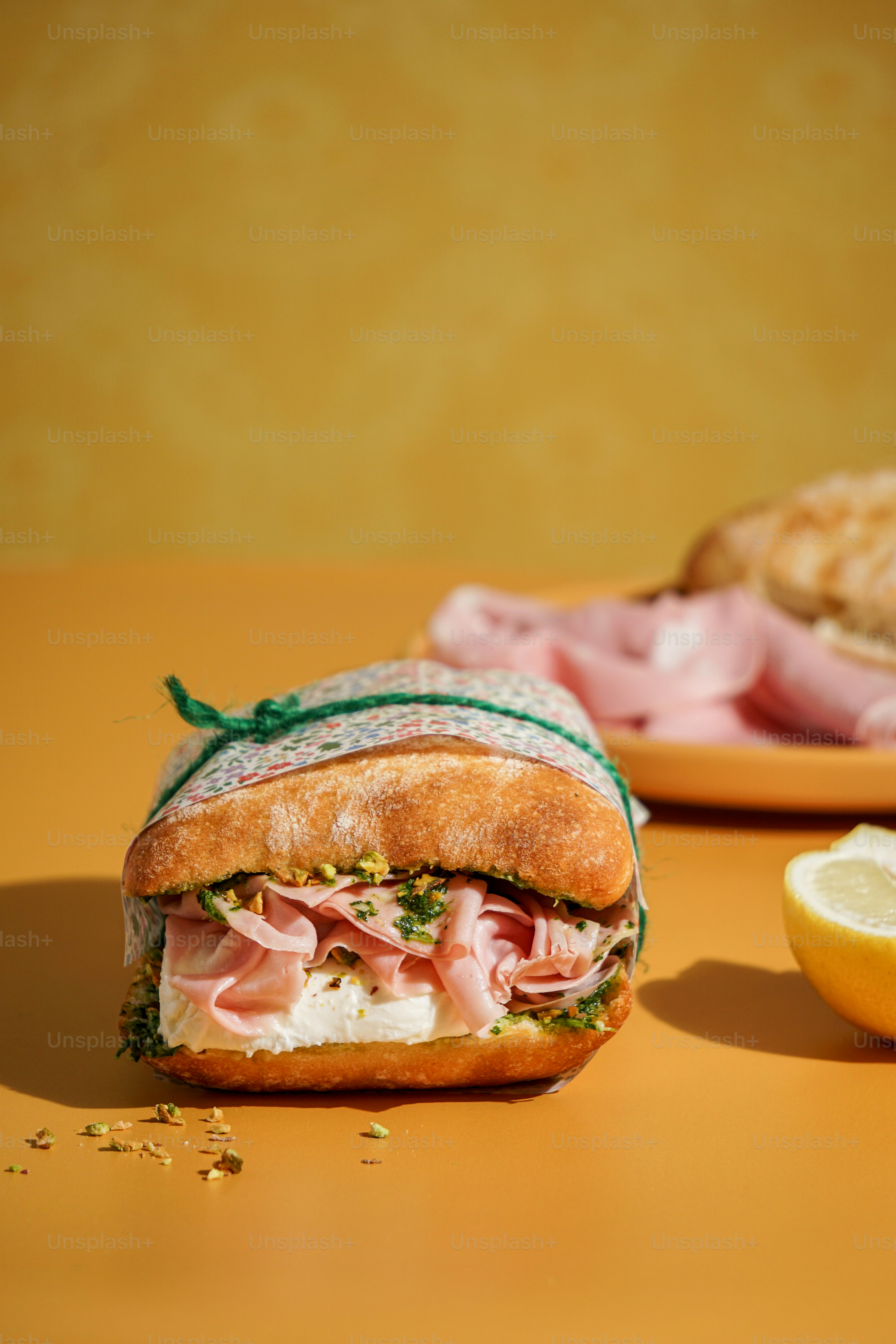 A sandwich with meat, cheese, and a lemon on a table
