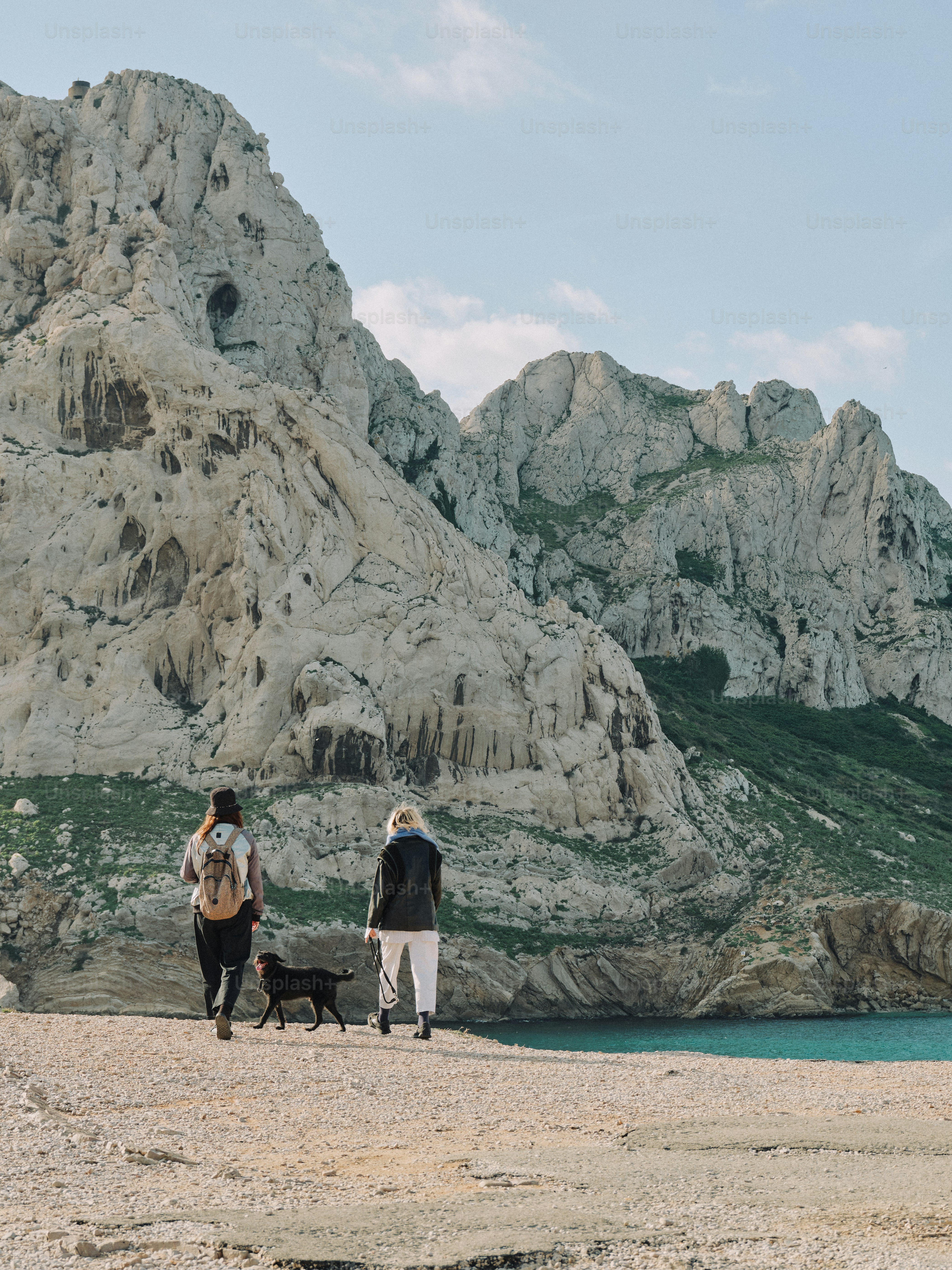 Menschen und Hund laufen an wunderschönen Klippen vorbei.
