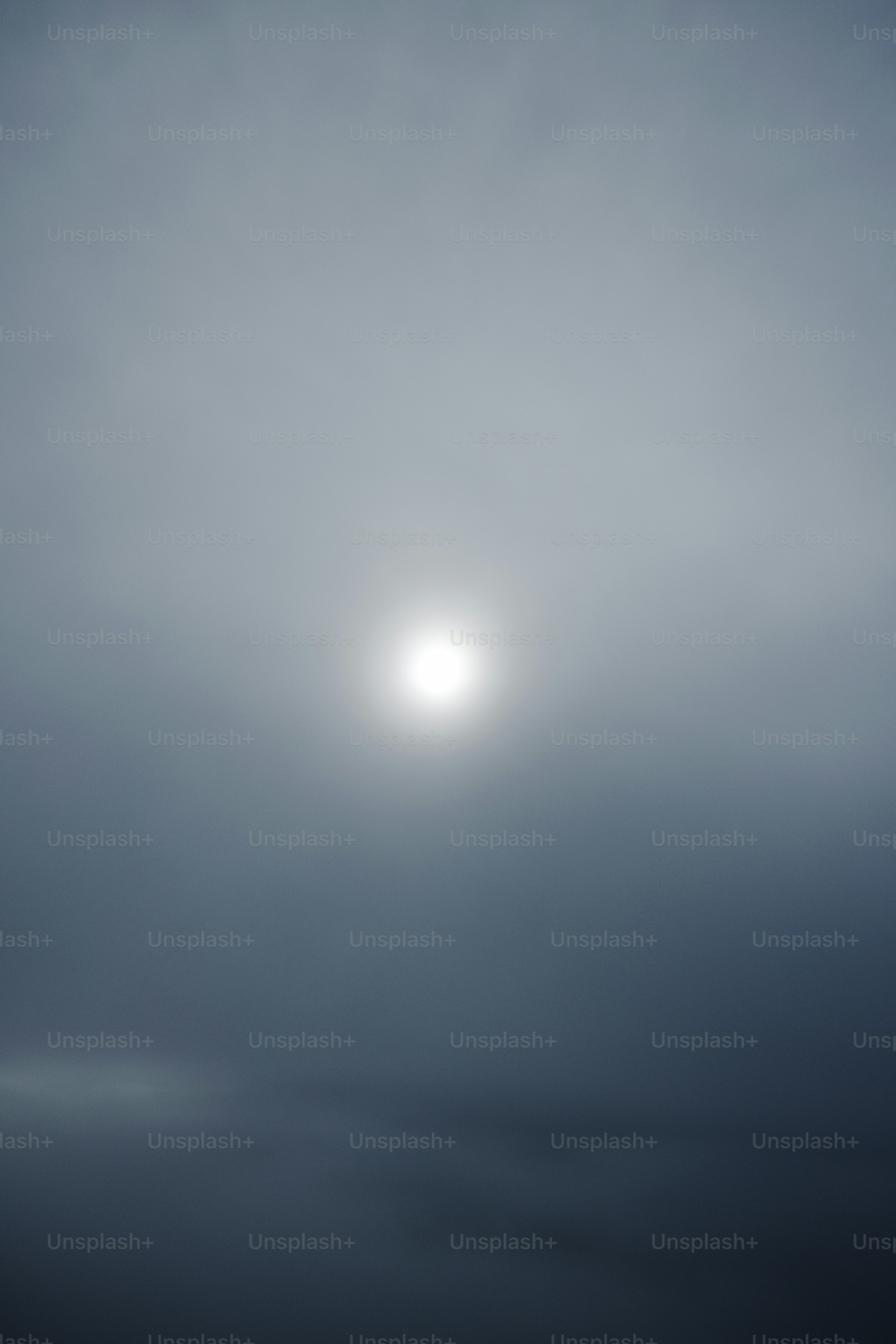 The sun is shining through the foggy sky