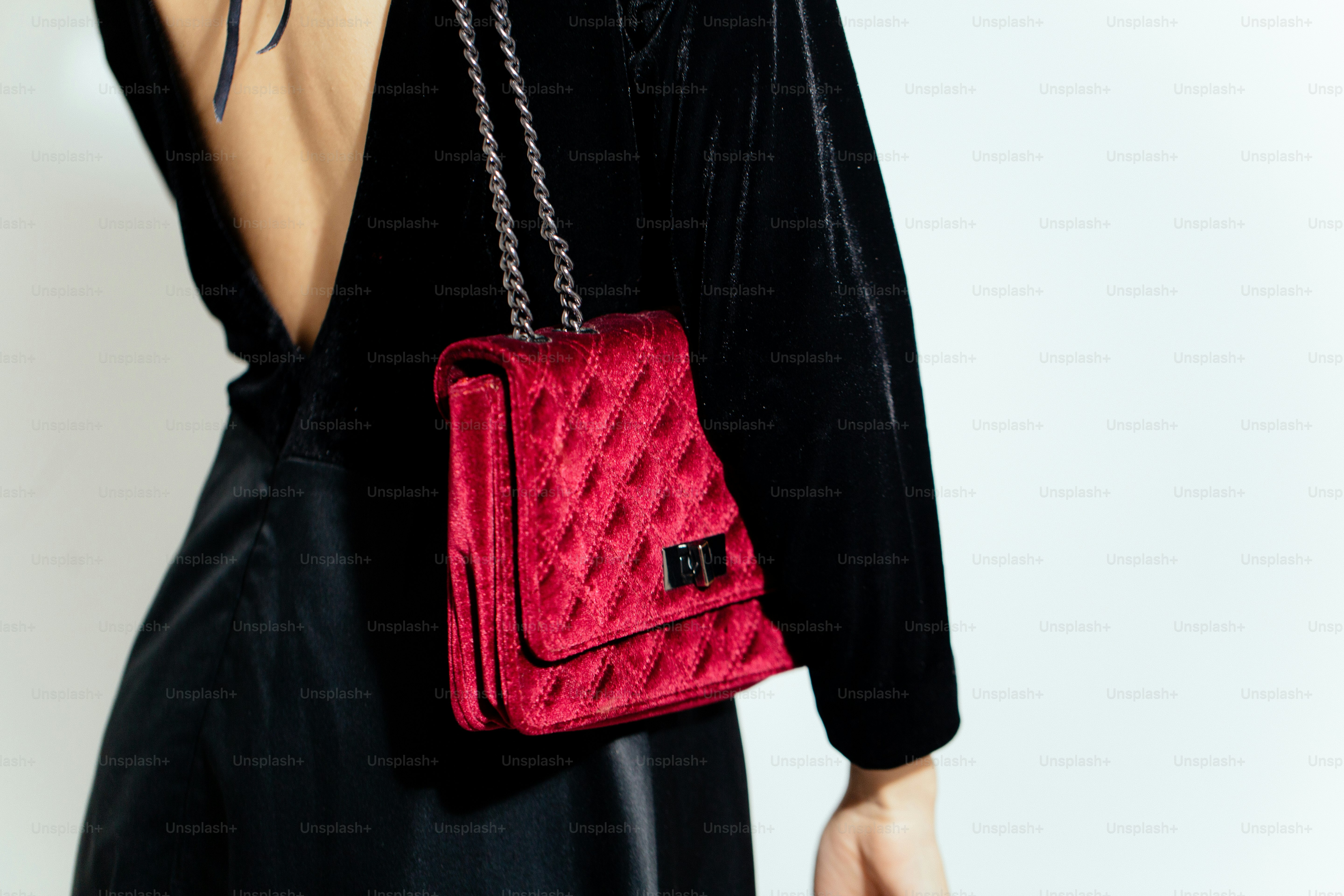 A woman in a black dress holding a red purse