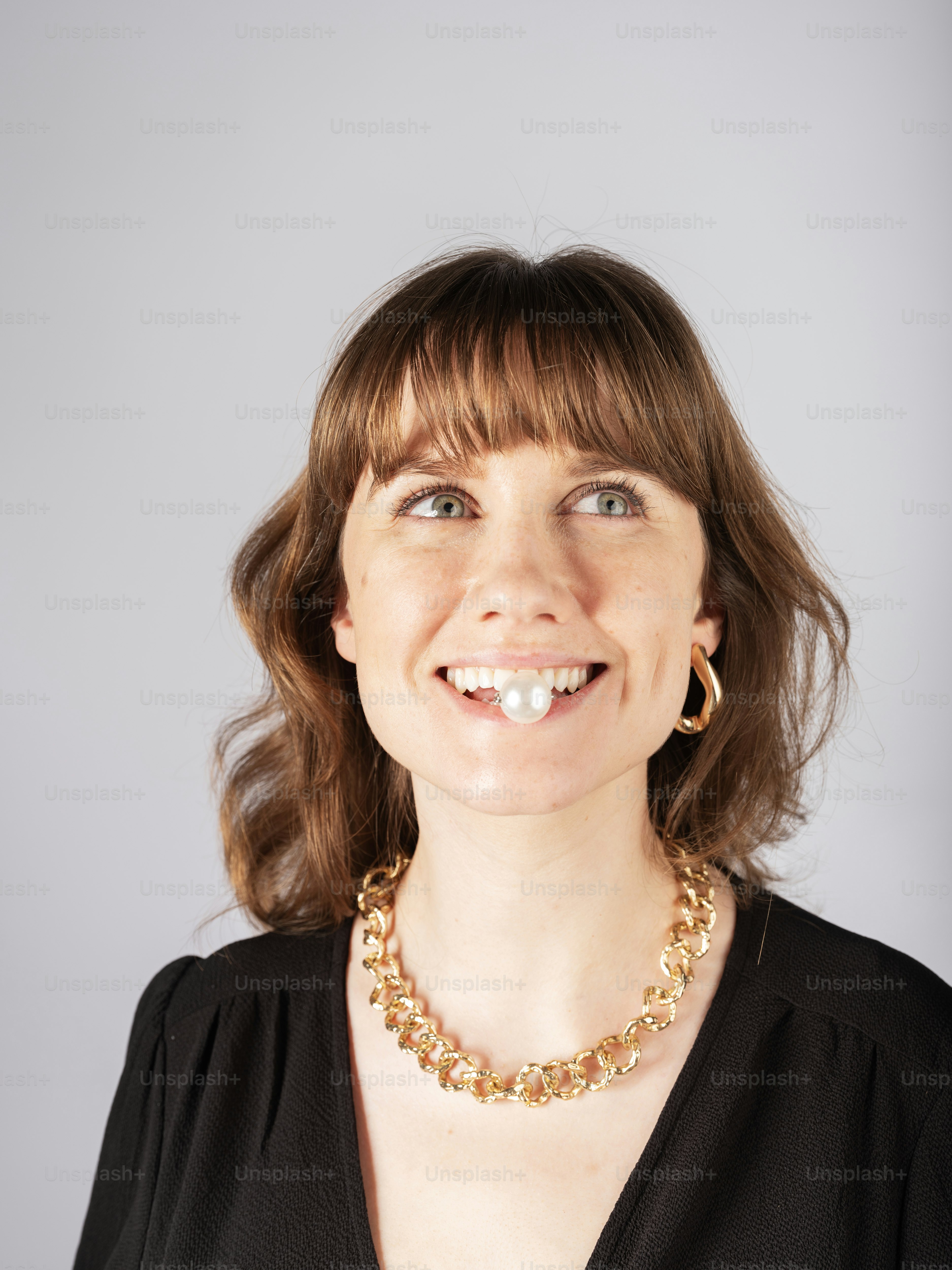 Une femme vêtue d’une chemise noire et d’un collier en or