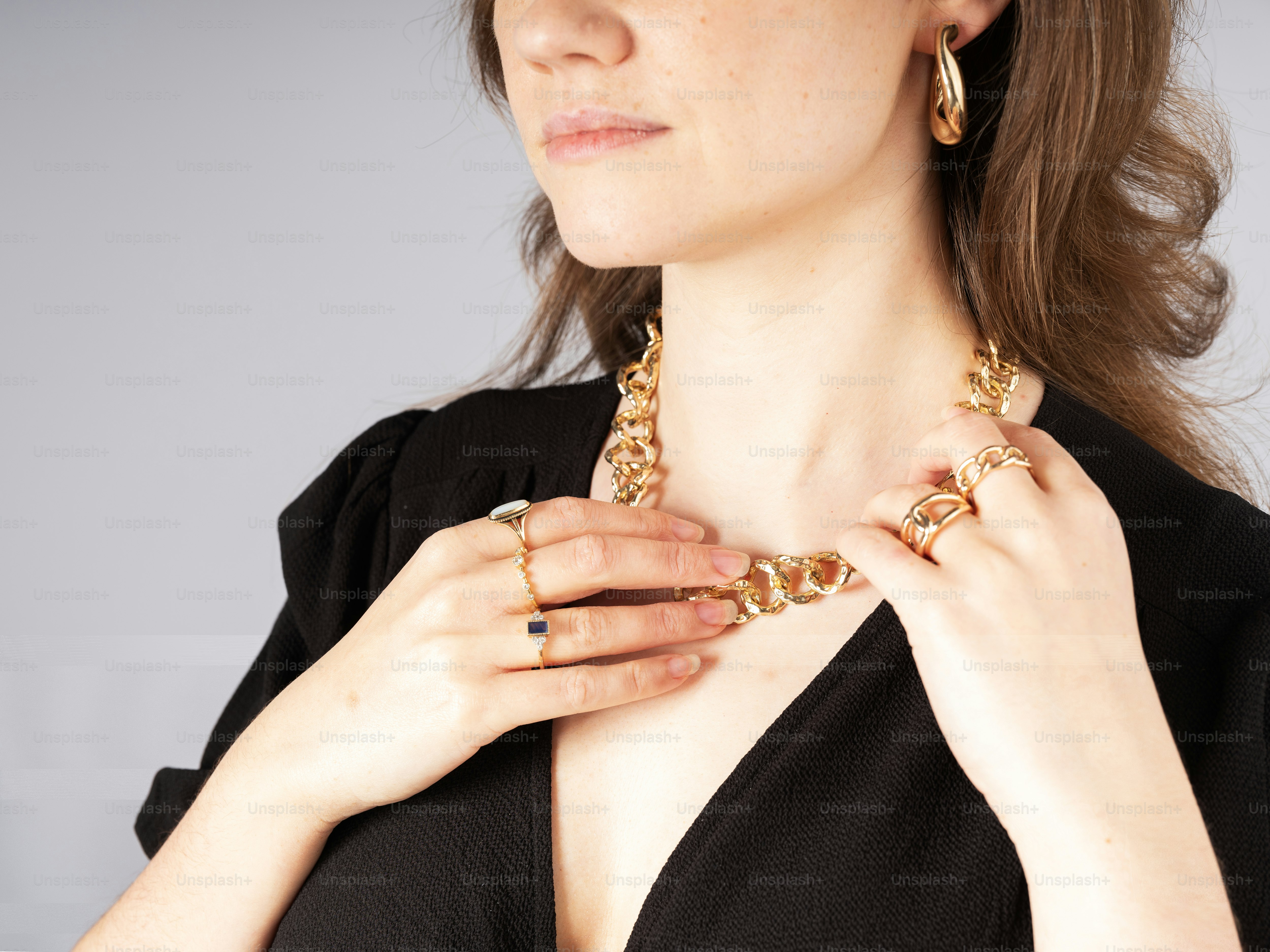 Une femme en robe noire porte un collier en or