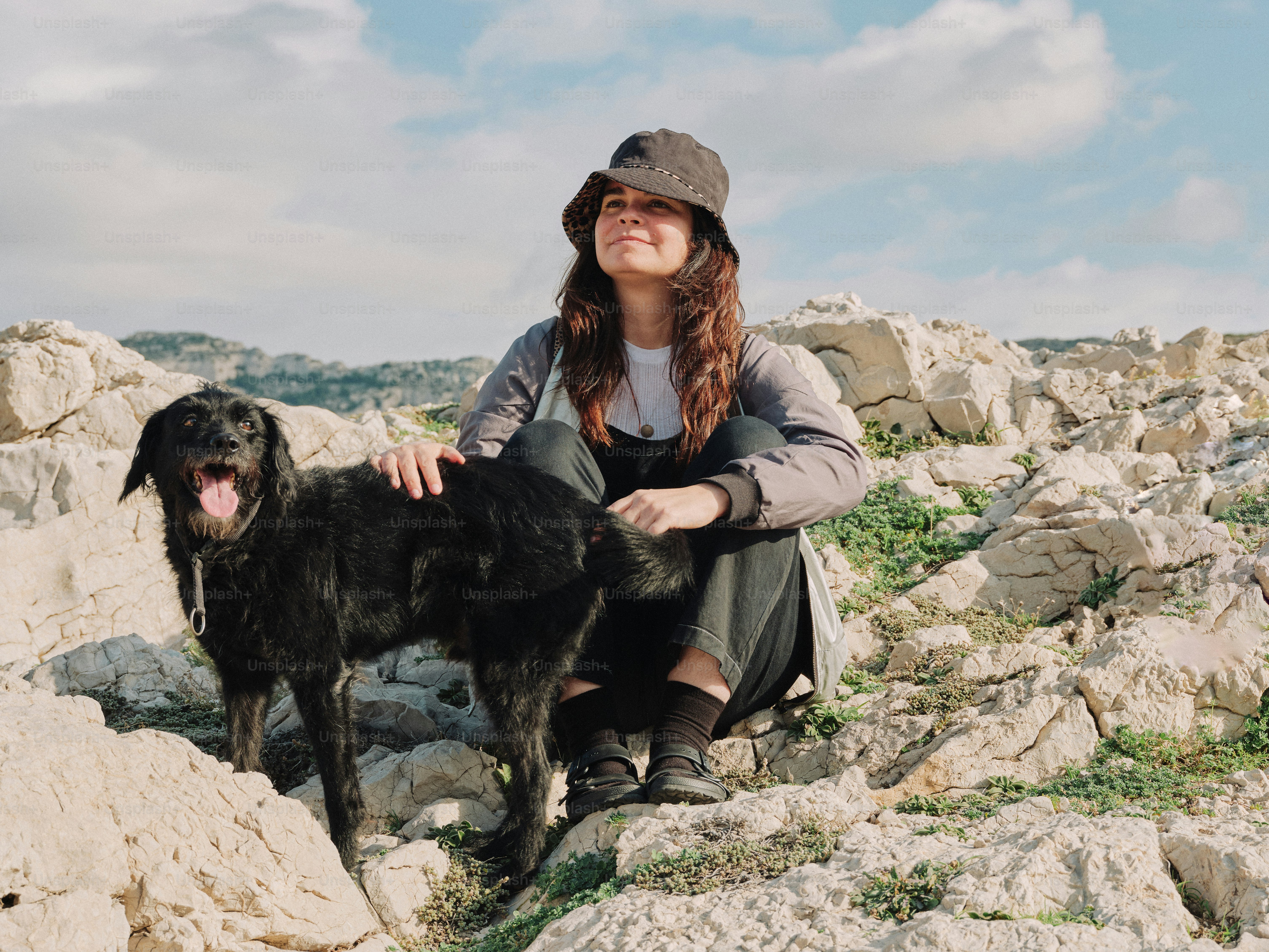 A woman sitting on rocks with a dog